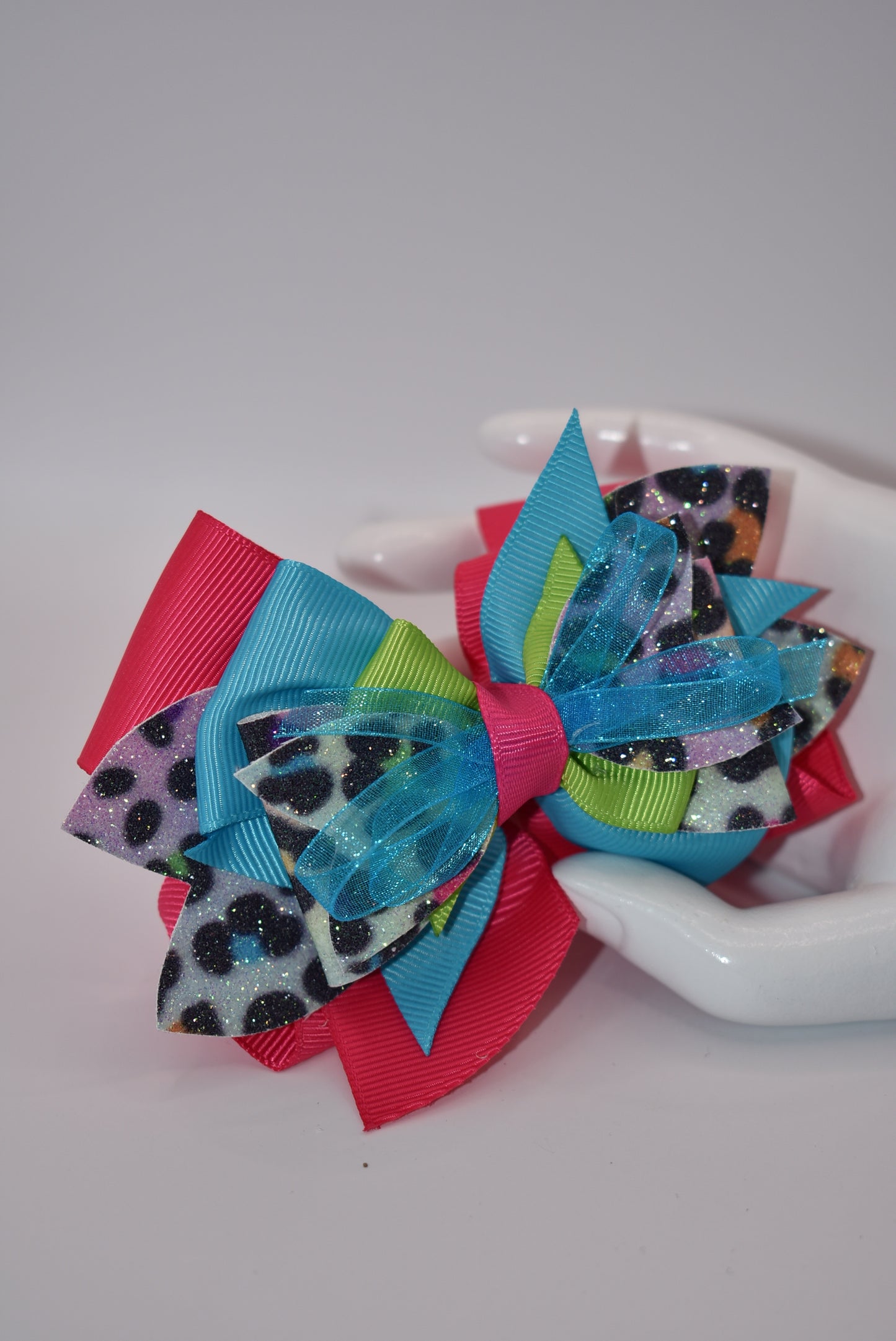 Unleash your wild side with Nana's Collection! Our crazy fun leopard print multi-colored bow is like all your favorite colors rolled into one. Made with faux leather and soft ribbon, this bow is fierce yet stylish. Secured with an alligator clip, it's the perfect accessory for any outfit. Go wild with Nana's Collection!