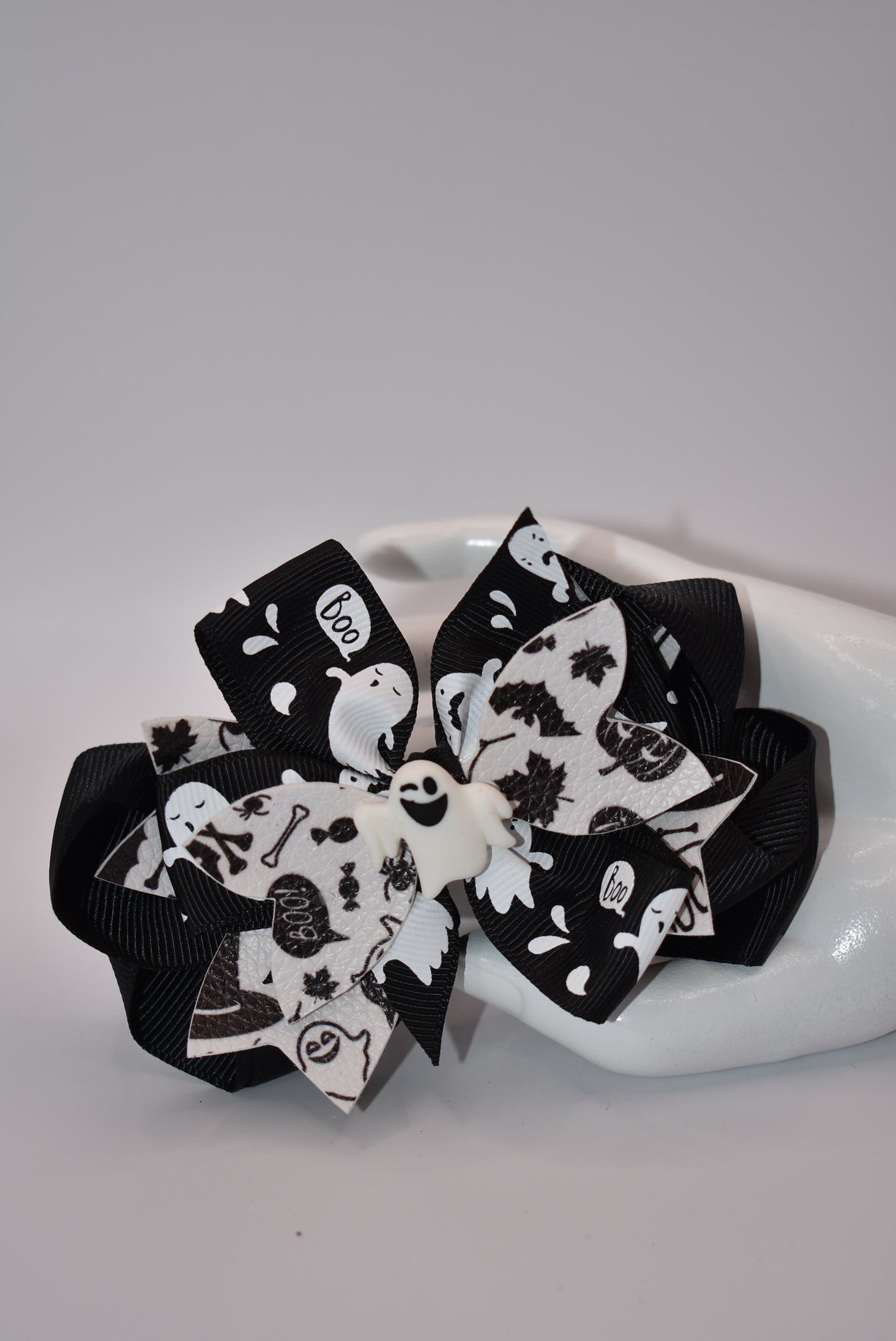 Get ready for Halloween with Nana's Collection! This hair bow features a playful combination of black and white, with a ghost motif and layers of fun ribbon. Complete with an aligator clip, it's the perfect accessory for a spooky look. (Boo-tiful!)