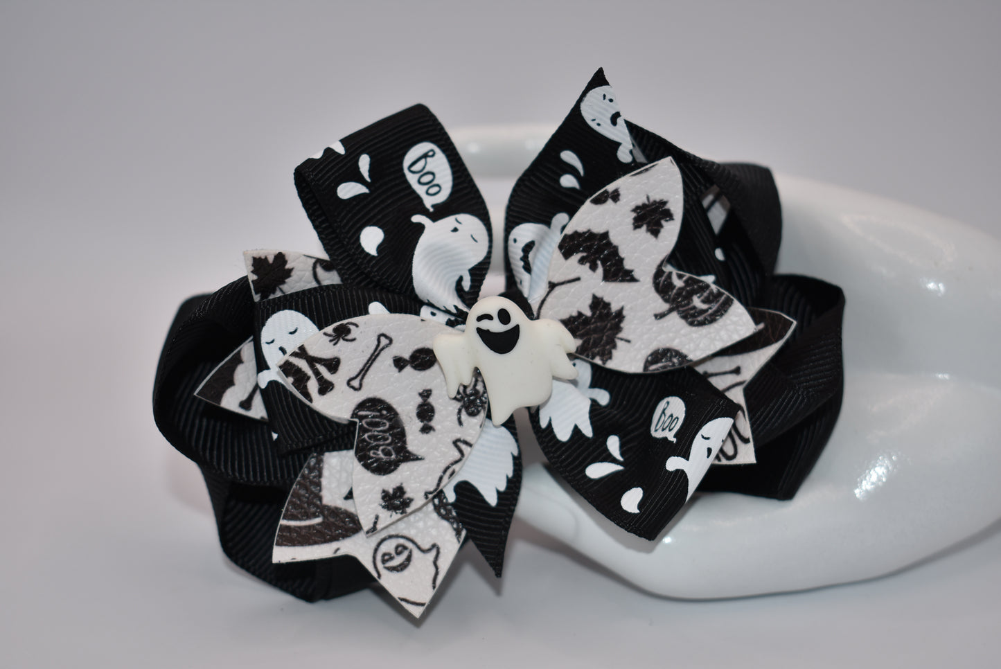 Get ready for Halloween with Nana's Collection! This hair bow features a playful combination of black and white, with a ghost motif and layers of fun ribbon. Complete with an aligator clip, it's the perfect accessory for a spooky look. (Boo-tiful!)