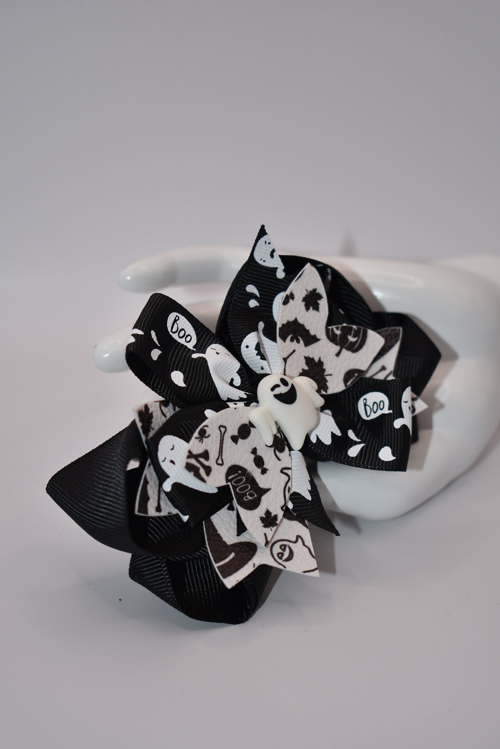 Get ready for Halloween with Nana's Collection! This hair bow features a playful combination of black and white, with a ghost motif and layers of fun ribbon. Complete with an aligator clip, it's the perfect accessory for a spooky look. (Boo-tiful!)