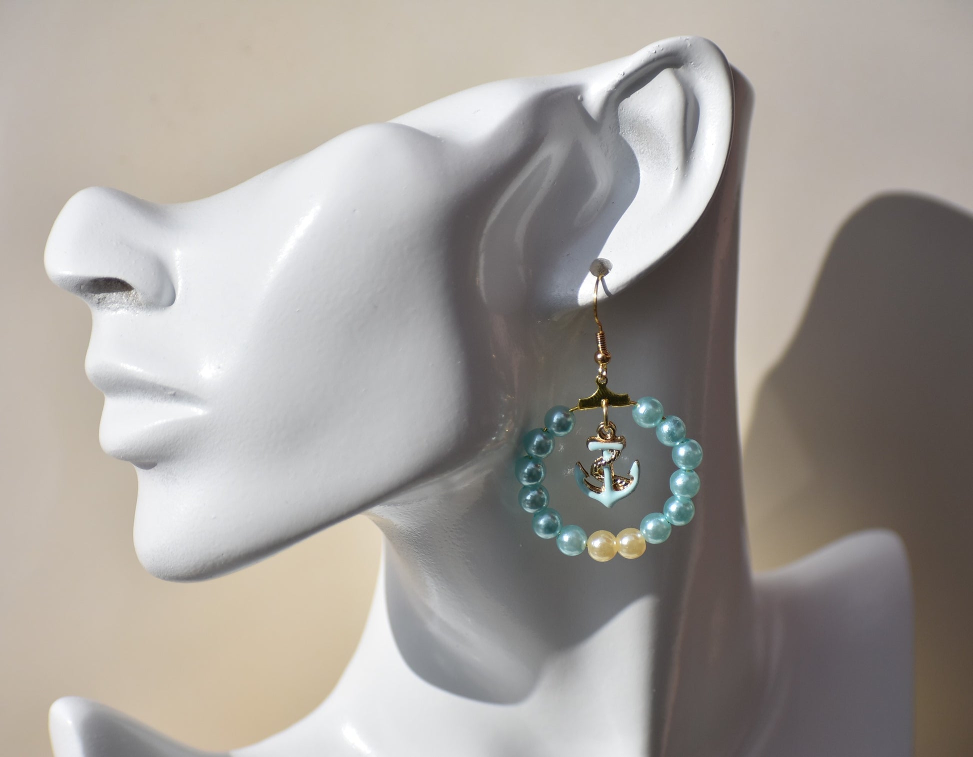 Our Nautical Collection 9 earrings feature aqua pearls with an aqua anchor charm in the center, all accented with a gold hooks. With their classic, elegant design, these earrings are sure to make a stunning addition to any look.