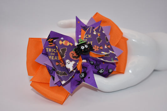 Add a playful touch to your Halloween outfit with our Nana's Collection! This super fun bow features plenty of purple, orange, and black colors, along with a cute Halloween charm on top. The alligator clip ensures comfort while adding a quirky, spooky element.