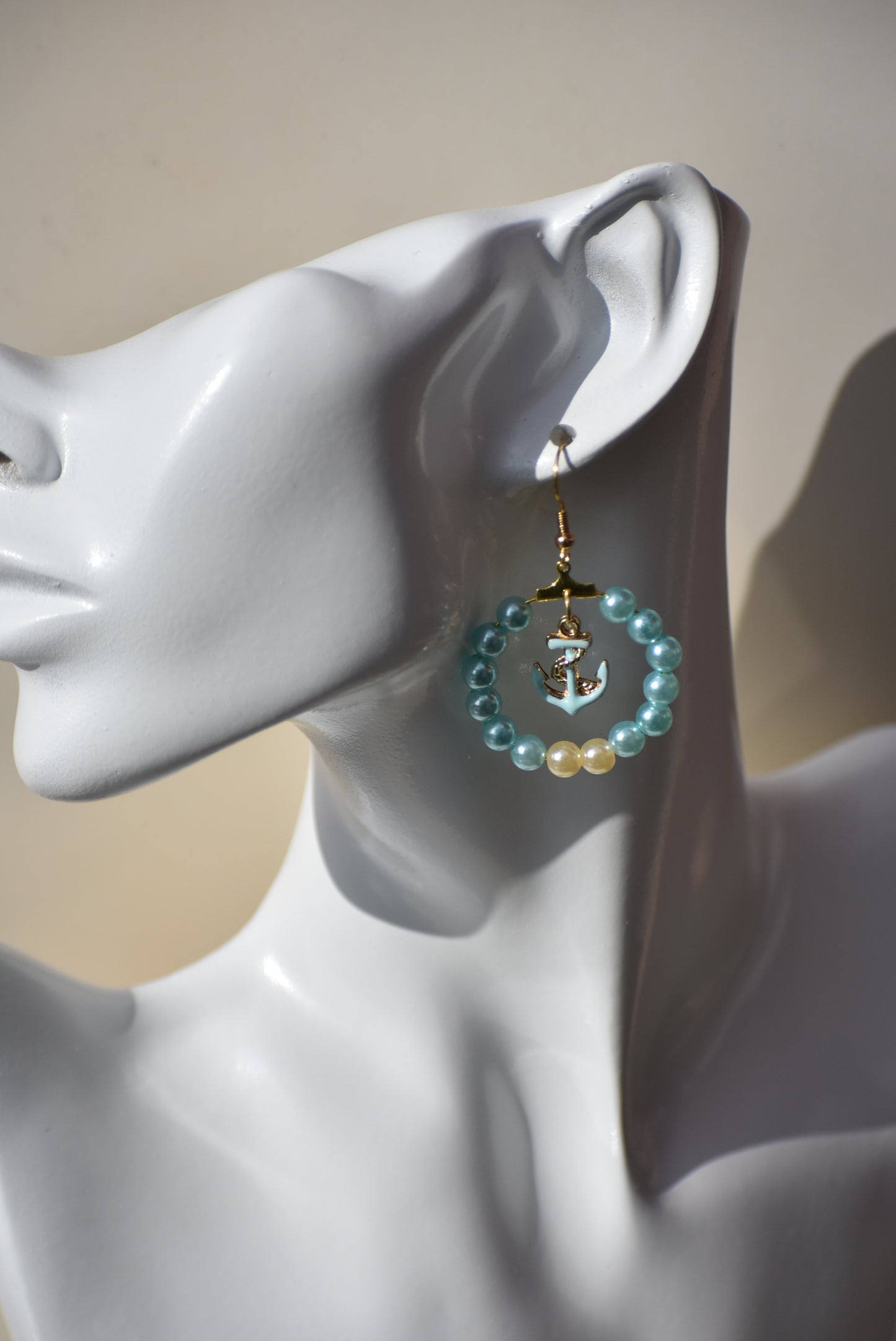 Our Nautical Collection 9 earrings feature aqua pearls with an aqua anchor charm in the center, all accented with a gold hooks. With their classic, elegant design, these earrings are sure to make a stunning addition to any look.