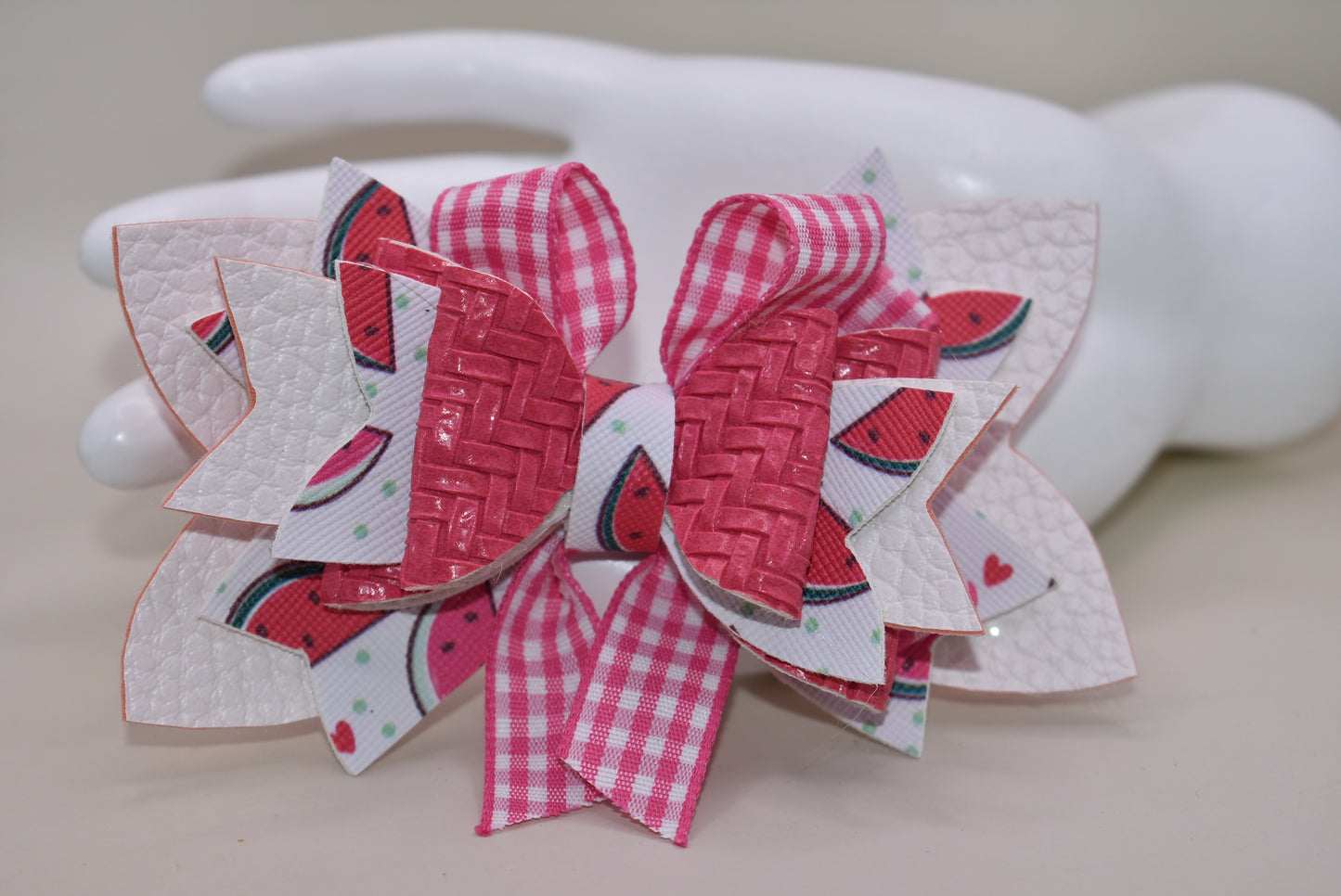 Introducing The Bow Corner! This adorable watermelon designed faux leather bow with a unique pink checkered accent is the perfect summer accessory for your little one. Its covered alligator clip makes for easy styling, while the playful pink and white colors add a fun touch to any outfit. Get ready to wow with this playful and stylish bow!