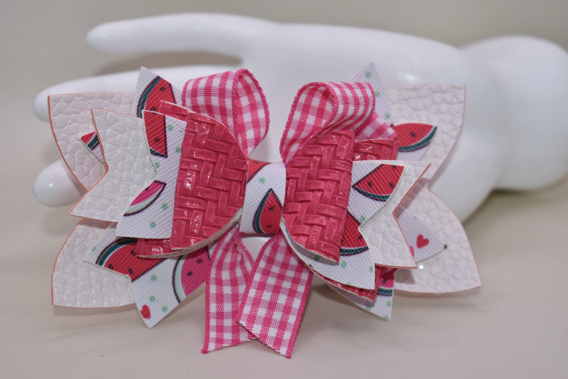 Introducing The Bow Corner! This adorable watermelon designed faux leather bow with a unique pink checkered accent is the perfect summer accessory for your little one. Its covered alligator clip makes for easy styling, while the playful pink and white colors add a fun touch to any outfit. Get ready to wow with this playful and stylish bow!