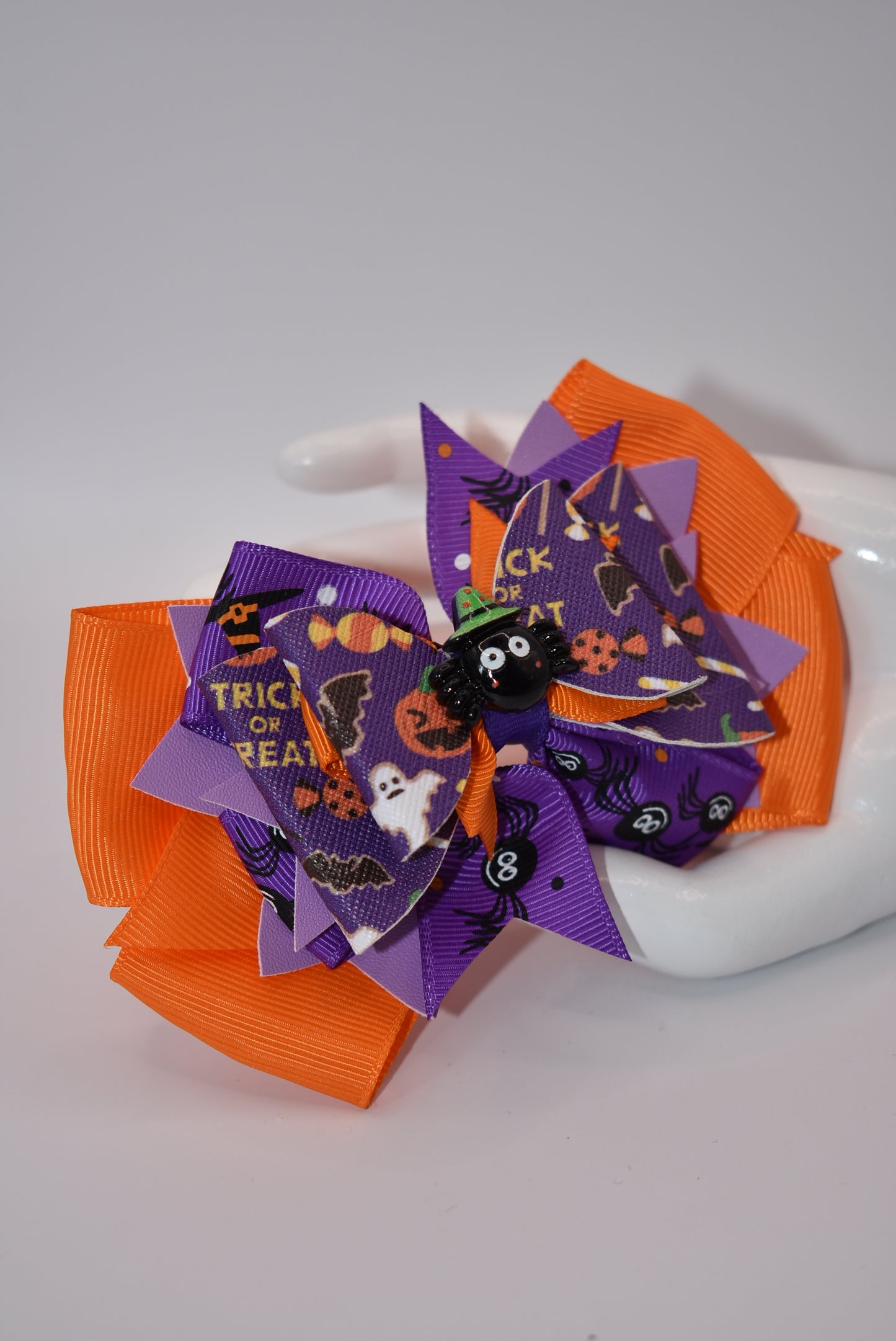 Add a playful touch to your Halloween outfit with our Nana's Collection! This super fun bow features plenty of purple, orange, and black colors, along with a cute Halloween charm on top. The alligator clip ensures comfort while adding a quirky, spooky element.