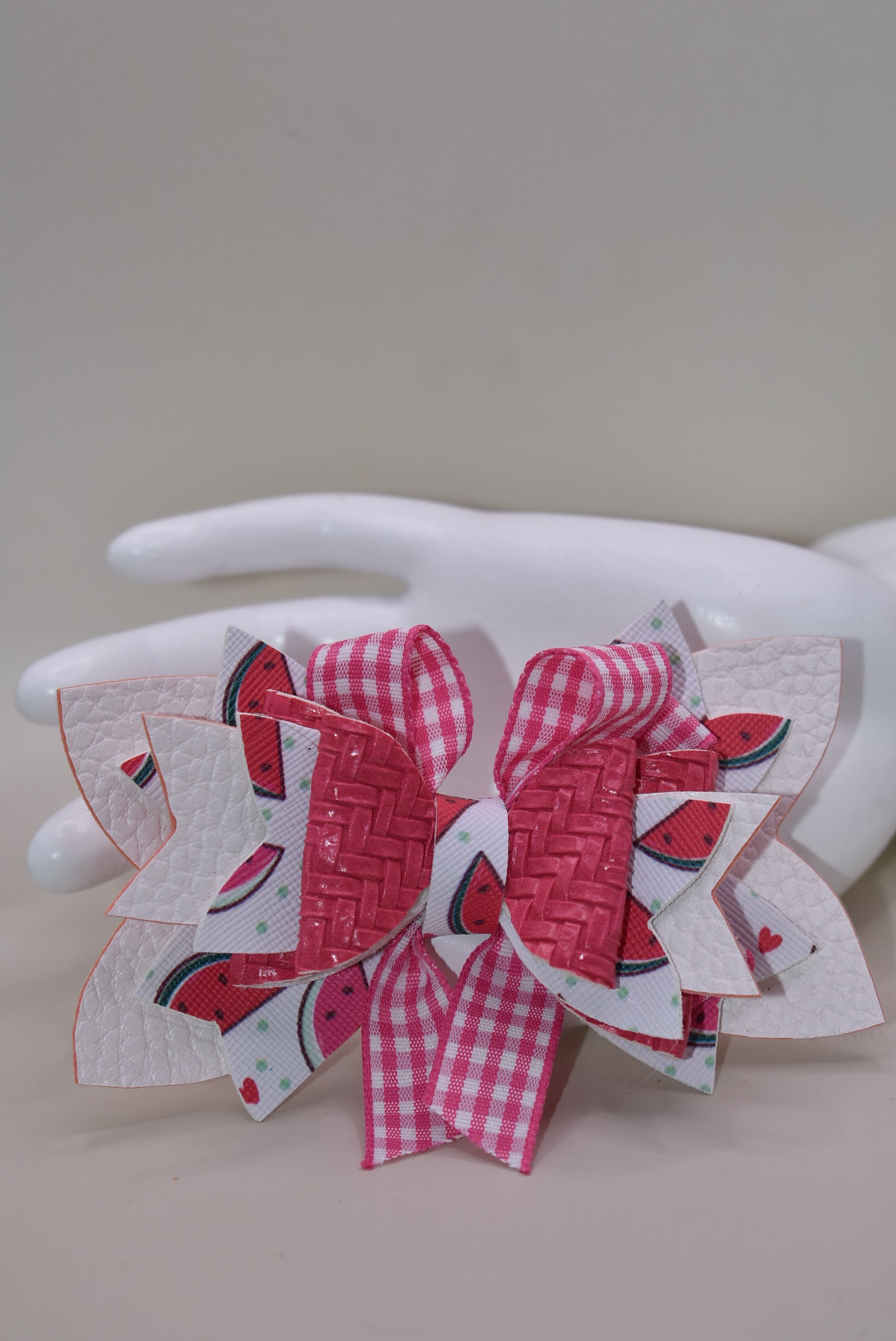 Introducing The Bow Corner! This adorable watermelon designed faux leather bow with a unique pink checkered accent is the perfect summer accessory for your little one. Its covered alligator clip makes for easy styling, while the playful pink and white colors add a fun touch to any outfit. Get ready to wow with this playful and stylish bow!