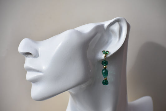 Make a statement with the Green Collection 14 earrings. Crafted with a gorgeous shade of green crystals mixed with gold beads, these earrings are guaranteed to make a lasting impression. The unique combination of colors is held together with green crystal posts, creating a stunning look for any special occasion. Truly a one-of-a-kind piece!