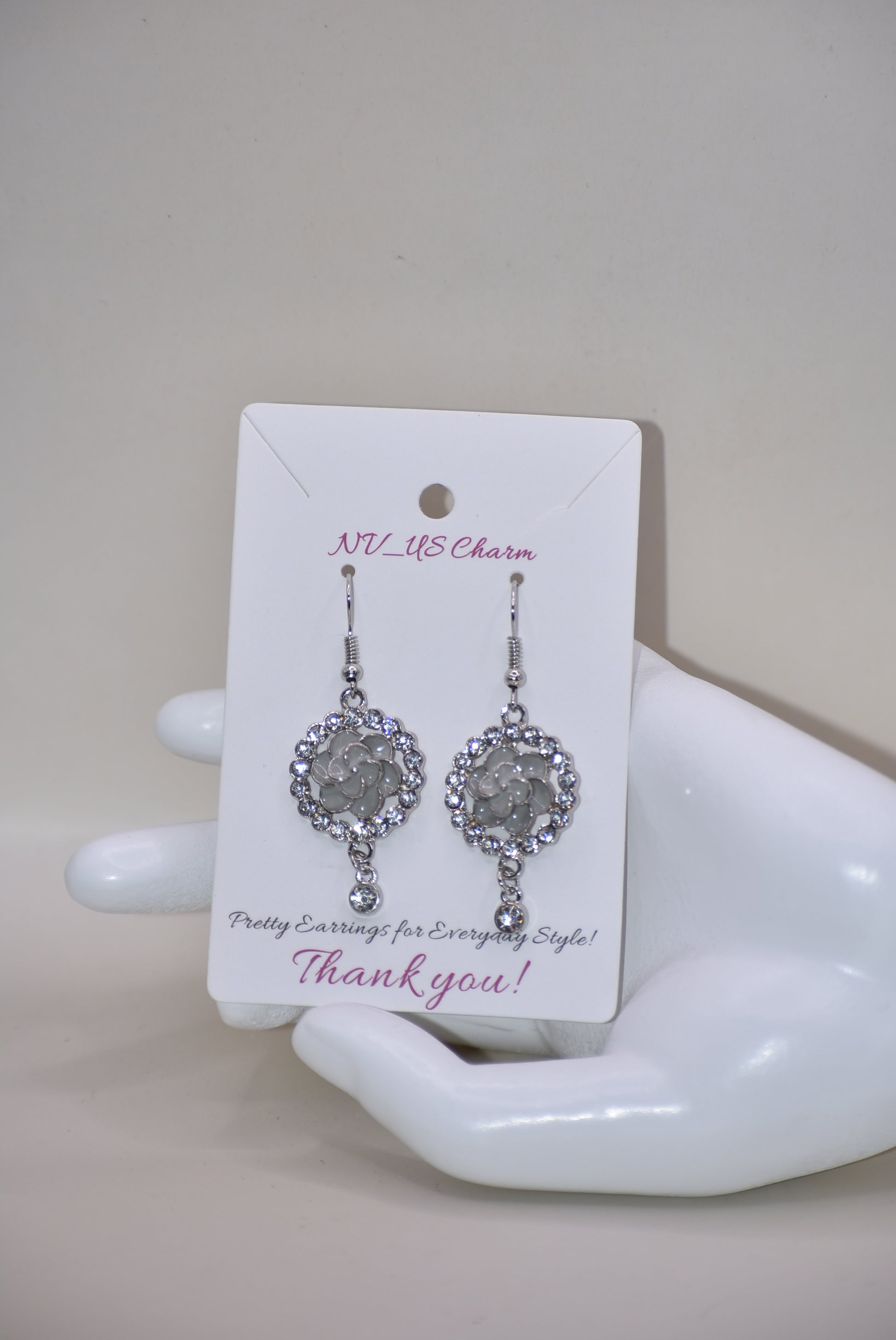 These Gray Collection 9 earrings provide a unique and sophisticated look. Featuring a pretty gray flower surrounded by crystals and a small crystal hanging, these silver hook earrings will add sparkle and elegance to any outfit. With intricate details and luxurious design, these earrings are a must-have addition to any jewelry collection.