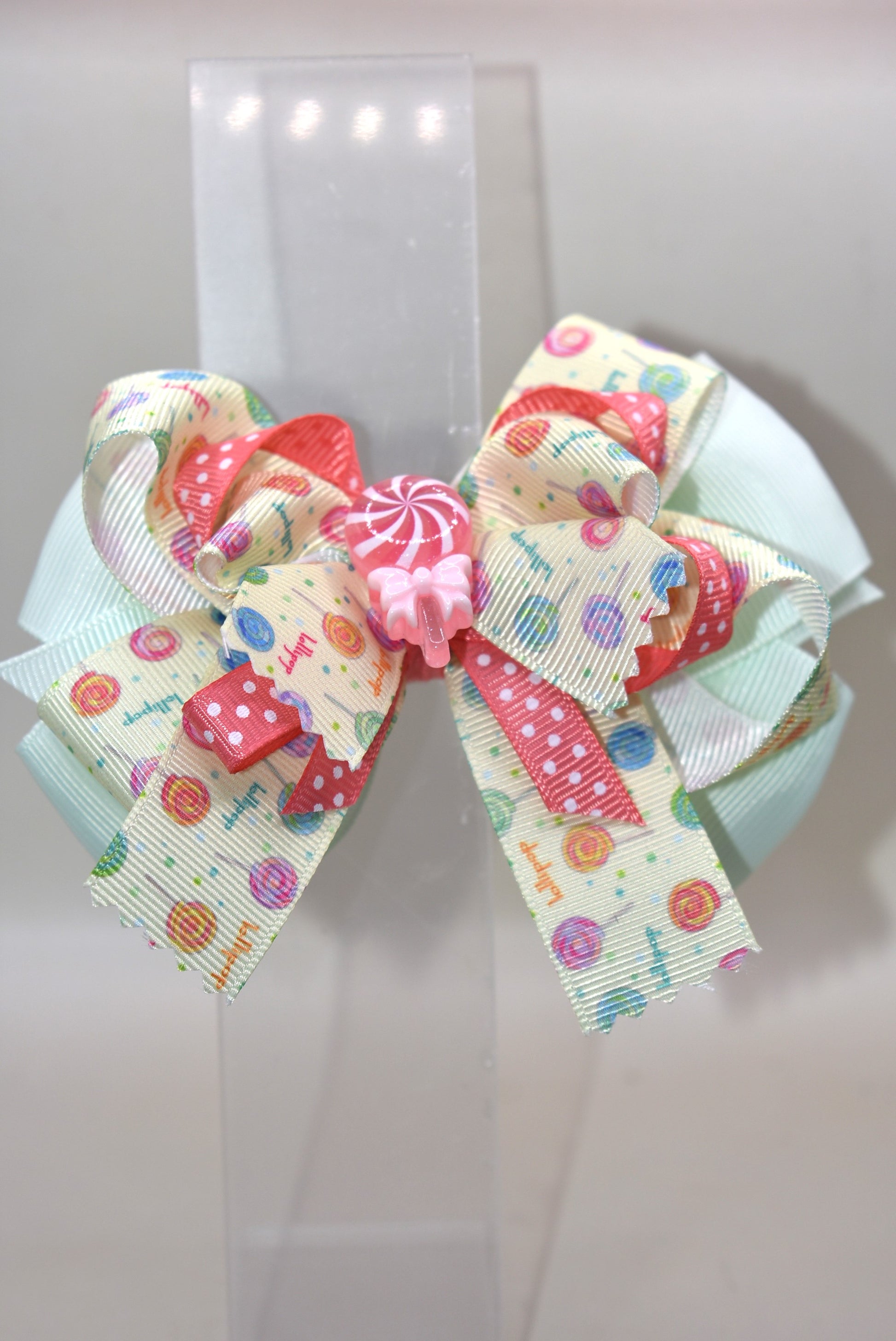 Add a pop of fun to your hair with Nana's Collection 66! Featuring a super fun lollipop bow with a cute charm on top, this ribbon combination of green and peach will make you stand out. The wrapped alligator clip adds comfort for all-day wear. 😍