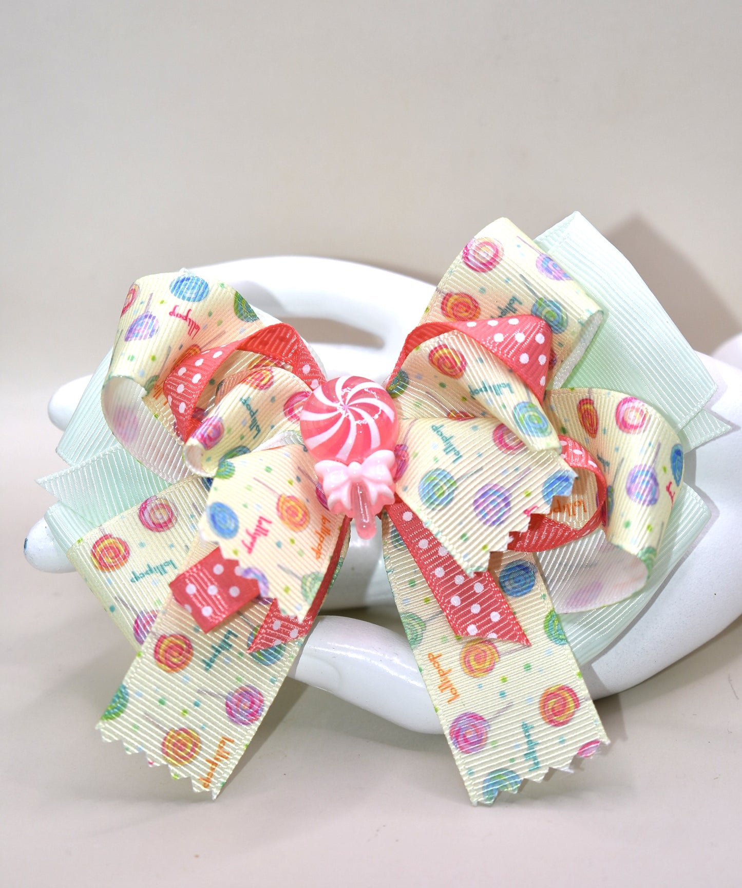 Add a pop of fun to your hair with Nana's Collection 66! Featuring a super fun lollipop bow with a cute charm on top, this ribbon combination of green and peach will make you stand out. The wrapped alligator clip adds comfort for all-day wear. 😍