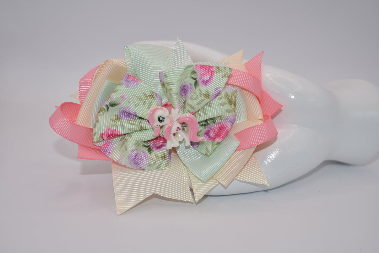 Introducing Nana's Collection - a charming mix of cream, pink, and soft green ribbons adorned with a delicate floral motif and an adorable horse charm. So elegant and stylish, this collection is perfect for adding a touch of whimsy to any outfit. A must-have for any fashionista.