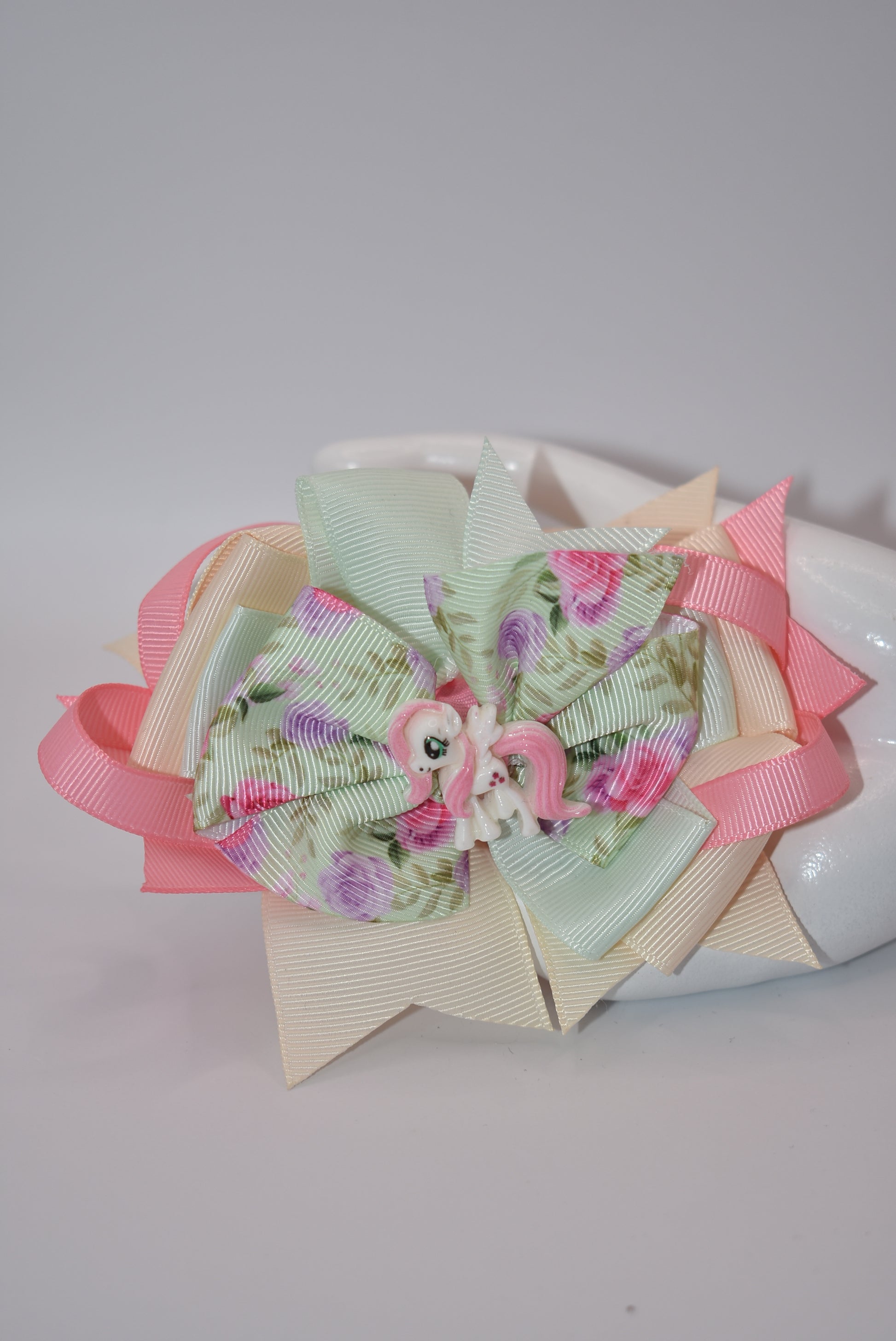 Introducing Nana's Collection - a charming mix of cream, pink, and soft green ribbons adorned with a delicate floral motif and an adorable horse charm. So elegant and stylish, this collection is perfect for adding a touch of whimsy to any outfit. A must-have for any fashionista.