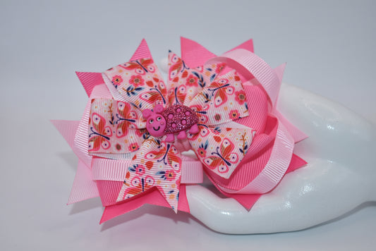 Introducing Nana's Collection - the bow with added cuteness! Adorned with a charming bug on soft pink ribbons, this alligator clip is not only stylish but comfortable too. A one-of-a-kind accessory that will bring smiles (and compliments) wherever you go!