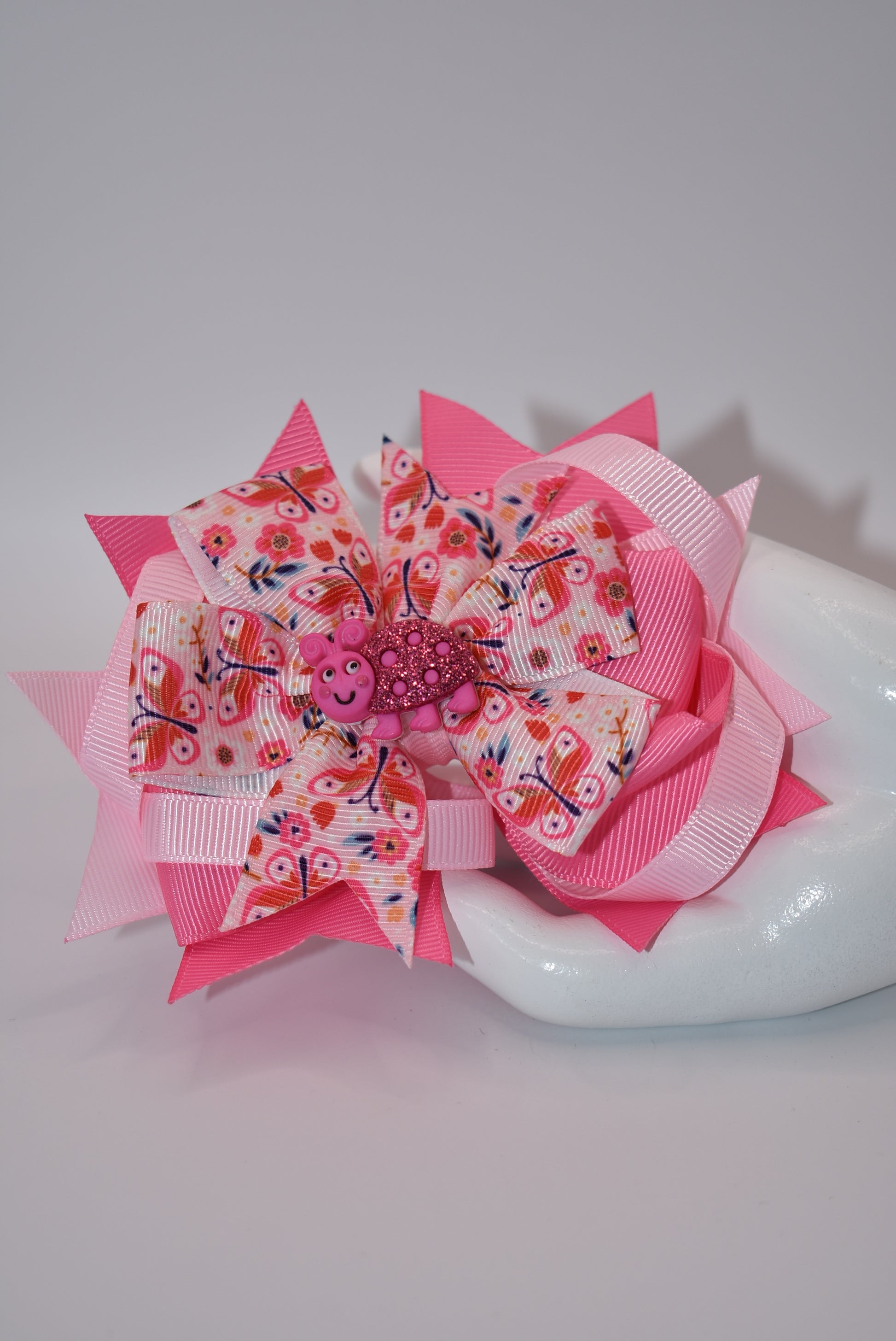 Introducing Nana's Collection - the bow with added cuteness! Adorned with a charming bug on soft pink ribbons, this alligator clip is not only stylish but comfortable too. A one-of-a-kind accessory that will bring smiles (and compliments) wherever you go!
