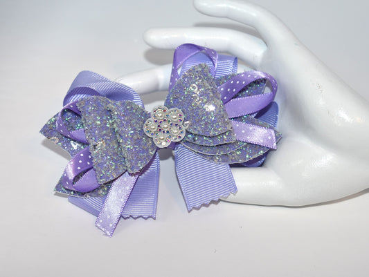 Add a splash of charm with this delightful accessory featuring a pretty lavender ribbon and sparkly faux leather, accented by a touch of purple satin polka dot ribbon 🎀. A shiny flower and a lovely pearl top it off for extra sparkle ✨. The alligator clip ensures a secure fit, wrapped comfortably for all-day wear. Perfect for adding a playful pop to any outfit! 🌸💜