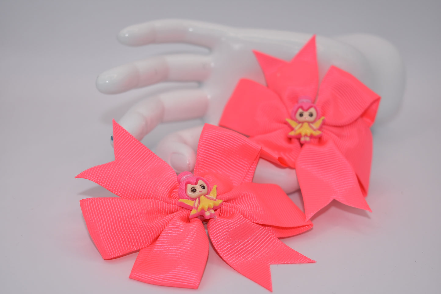 Add a touch of whimsy to your little girl's pigtails with Nana's Collection! This set of two pretty pink bows features adorable fairy designs on top to keep her safe. Plus, the alligator clip ensures a secure fit. Perfect for any playful princess!