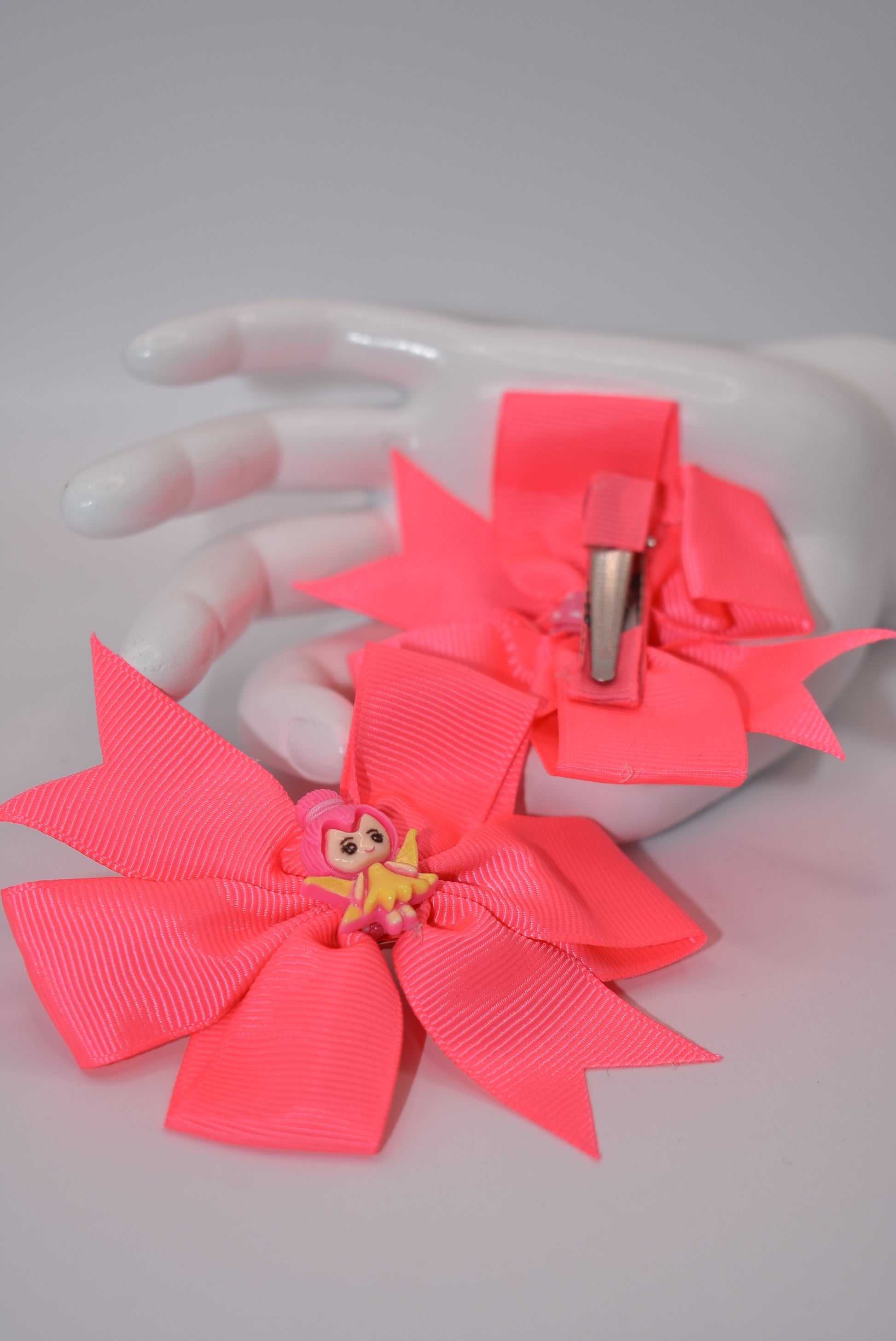 Add a touch of whimsy to your little girl's pigtails with Nana's Collection! This set of two pretty pink bows features adorable fairy designs on top to keep her safe. Plus, the alligator clip ensures a secure fit. Perfect for any playful princess!