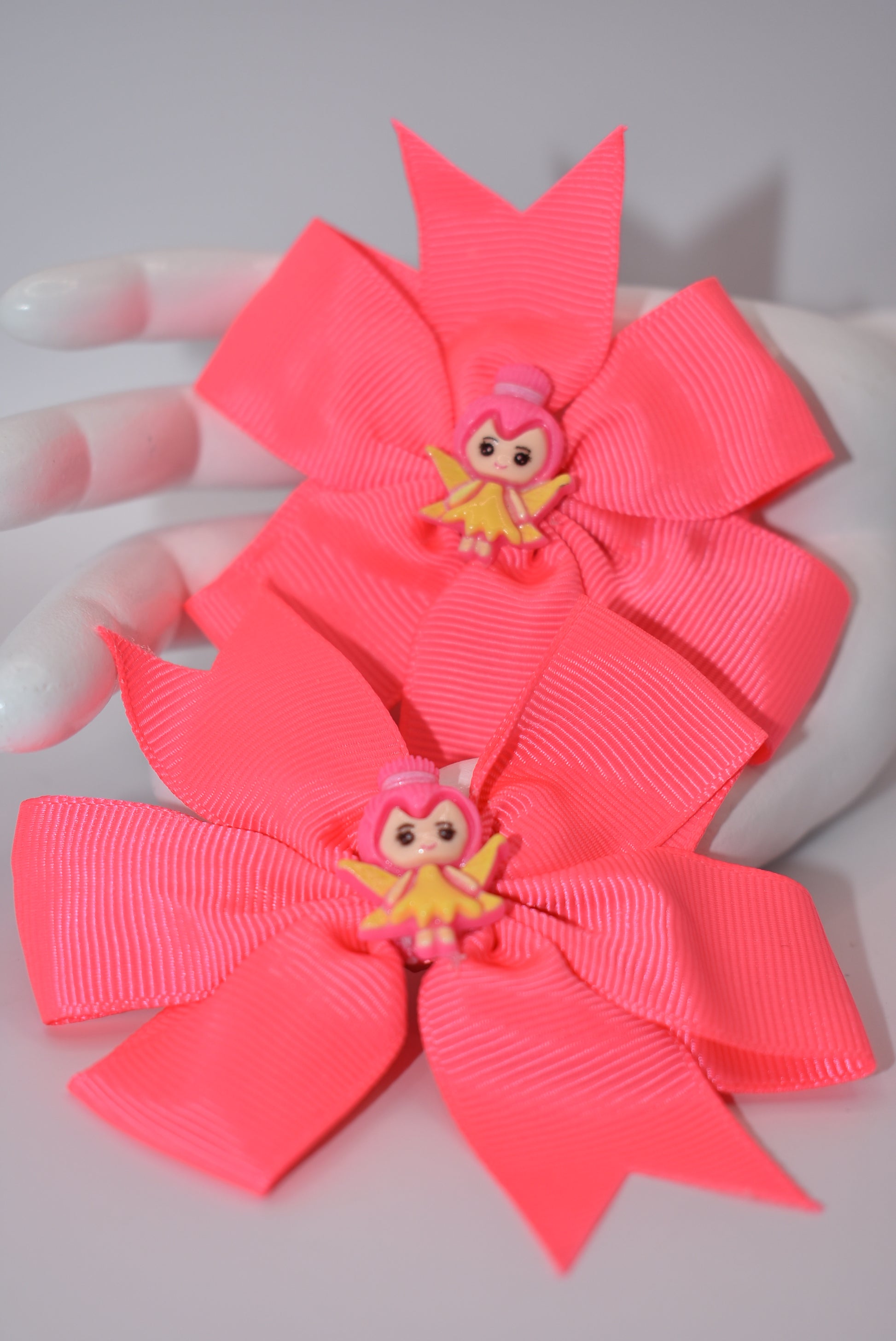 Add a touch of whimsy to your little girl's pigtails with Nana's Collection! This set of two pretty pink bows features adorable fairy designs on top to keep her safe. Plus, the alligator clip ensures a secure fit. Perfect for any playful princess!