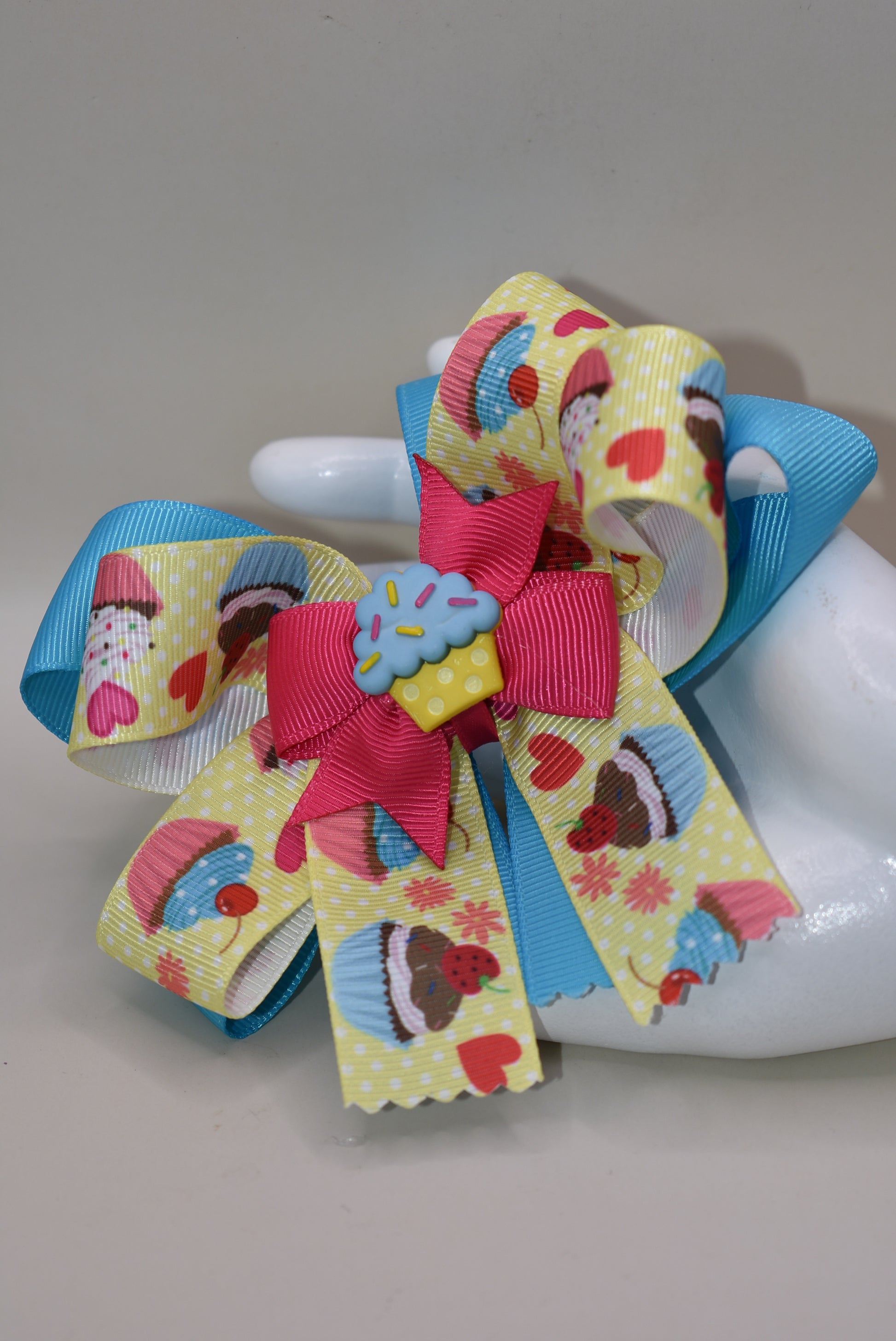 Indulge in Nana's Collection 71, featuring a playful bow with an adorable cupcake charm. The covered alligator clip makes for easy wear, perfect for any occasion. Satisfy your sweet tooth with this fun and quirky cupcake 