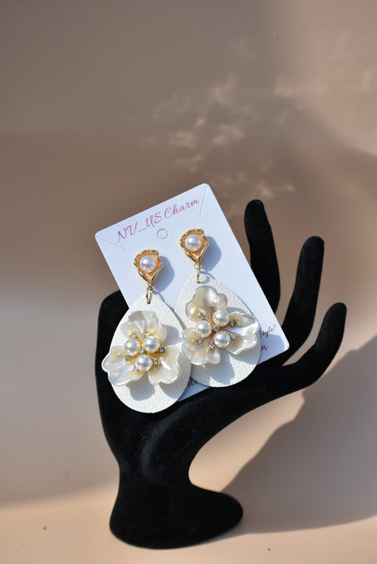 Immerse yourself in one-of-a-kind beauty with the Wedding Collection 5 earrings. Blending a cream faux leather teardrop with a stunning pearl flower center, these earrings will set you apart from everyone else. They hang from gold pearl posts for comfort, making them perfect for any special occasion.