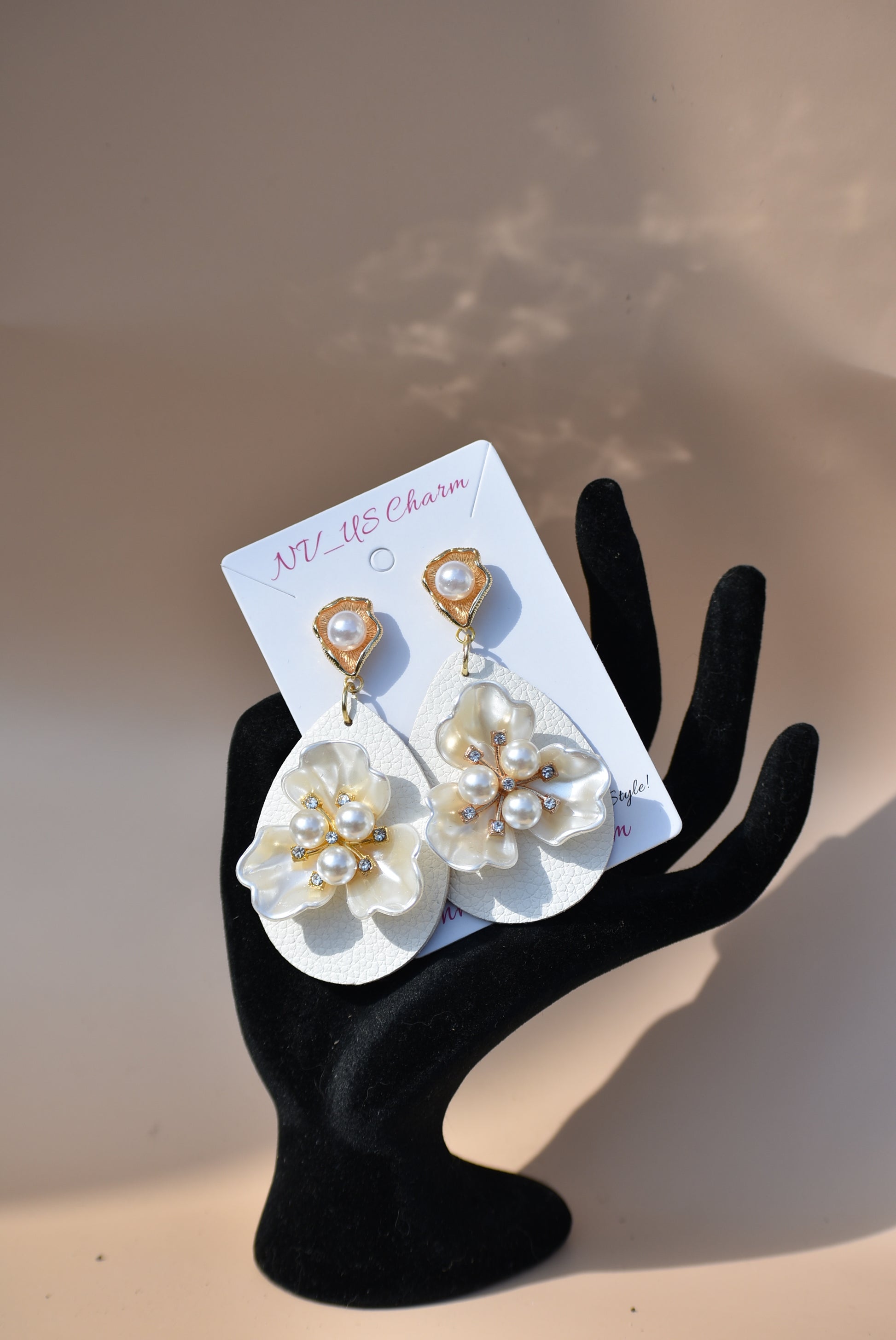 .Immerse yourself in one-of-a-kind beauty with the Wedding Collection 5 earrings. Blending a cream faux leather teardrop with a stunning pearl flower center, these earrings will set you apart from everyone else. They hang from gold pearl posts for comfort, making them perfect for any special occasion.