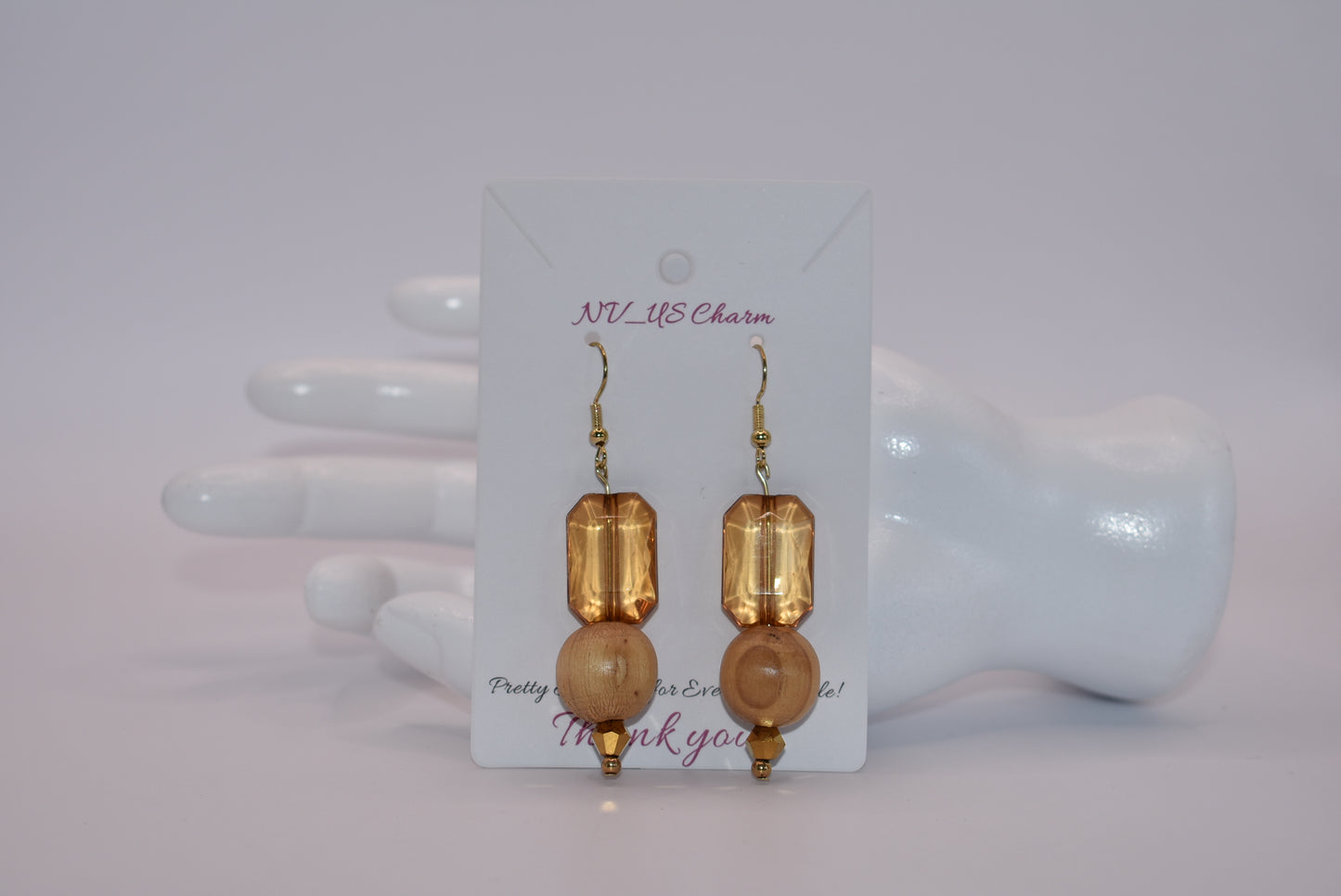 Add some playful charm to your outfit with these gold hypoallergenic hook earrings. Featuring an amber gem with a round wood bead and small beading at the bottom, they are perfect for dressing up or down. A must-have addition to any wardrobe!