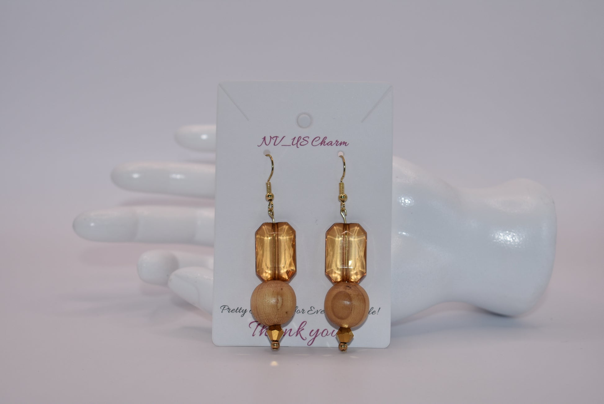 Add some playful charm to your outfit with these gold hypoallergenic hook earrings. Featuring an amber gem with a round wood bead and small beading at the bottom, they are perfect for dressing up or down. A must-have addition to any wardrobe!