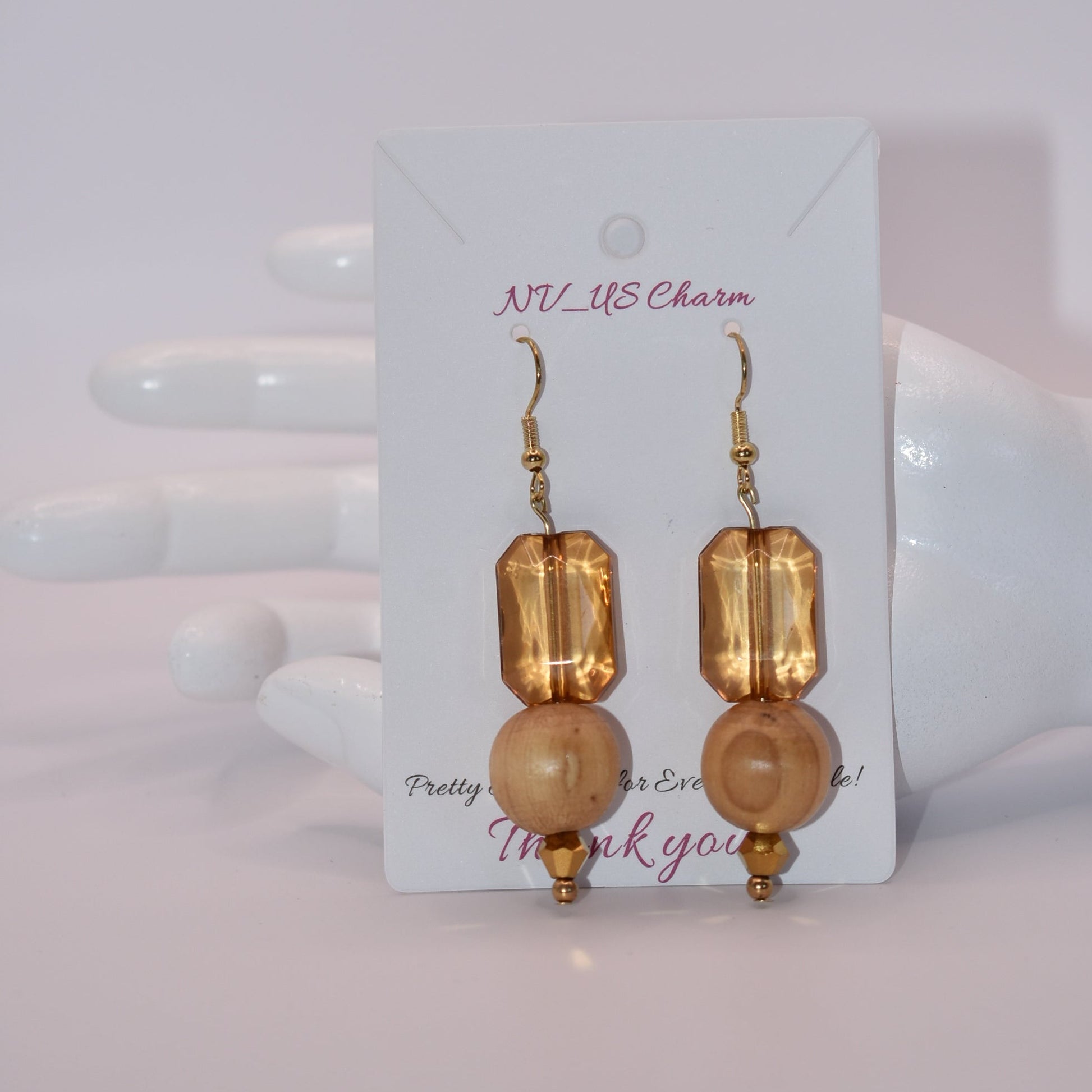 Add some playful charm to your outfit with these gold hypoallergenic hook earrings. Featuring an amber gem with a round wood bead and small beading at the bottom, they are perfect for dressing up or down. A must-have addition to any wardrobe!