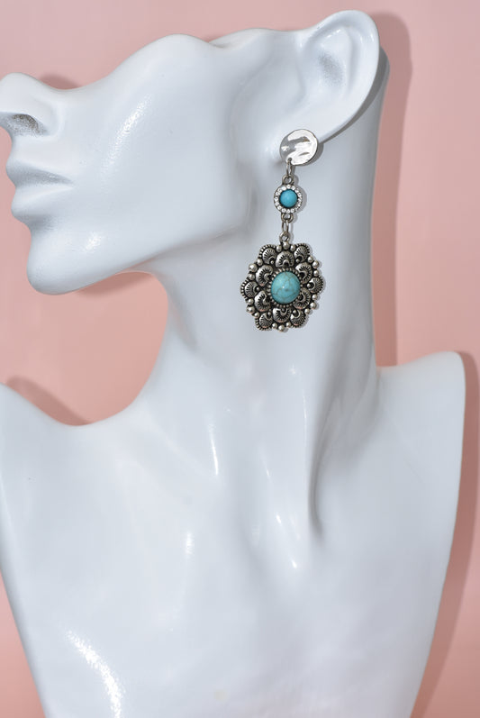 Introducing the Western Collection silver post earrings, designed to add a touch of understated elegance to any outfit. Each earring features a turquoise connector that holds a delicate filigree flower, accented by a turquoise center. Whether you're dressing up or down, these earrings are sure to give your look a dynamic cowgirl flair.