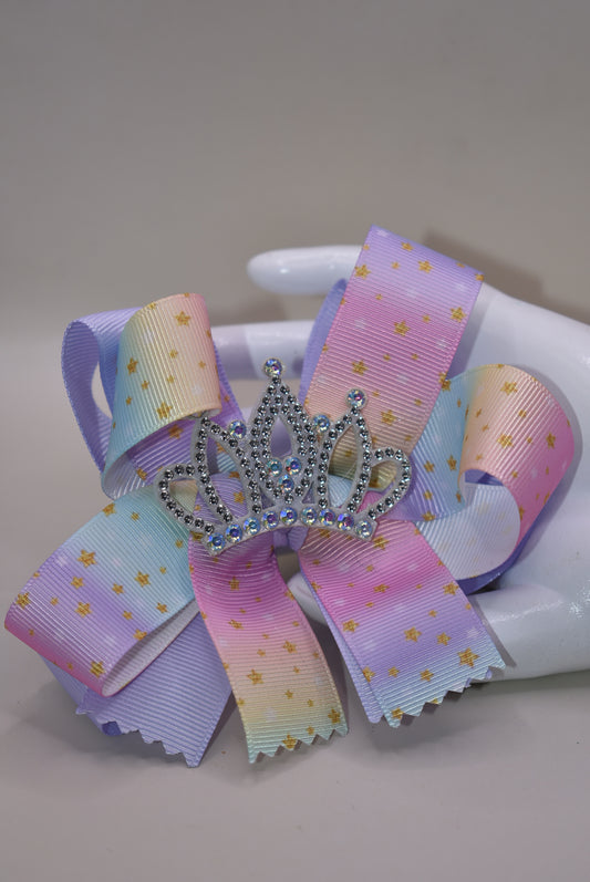 Nana's Collection presents the Perfect Princess Bow! 👑✨ This soft rainbow-colored beauty is adorned with pretty gold stars ⭐ and topped with a big sparkly crown 👸 for that royal touch! The wrapped alligator clip ensures all-day wear without slipping. 🌈 Transform any outfit into a majestic ensemble fit for your little princess! 💖