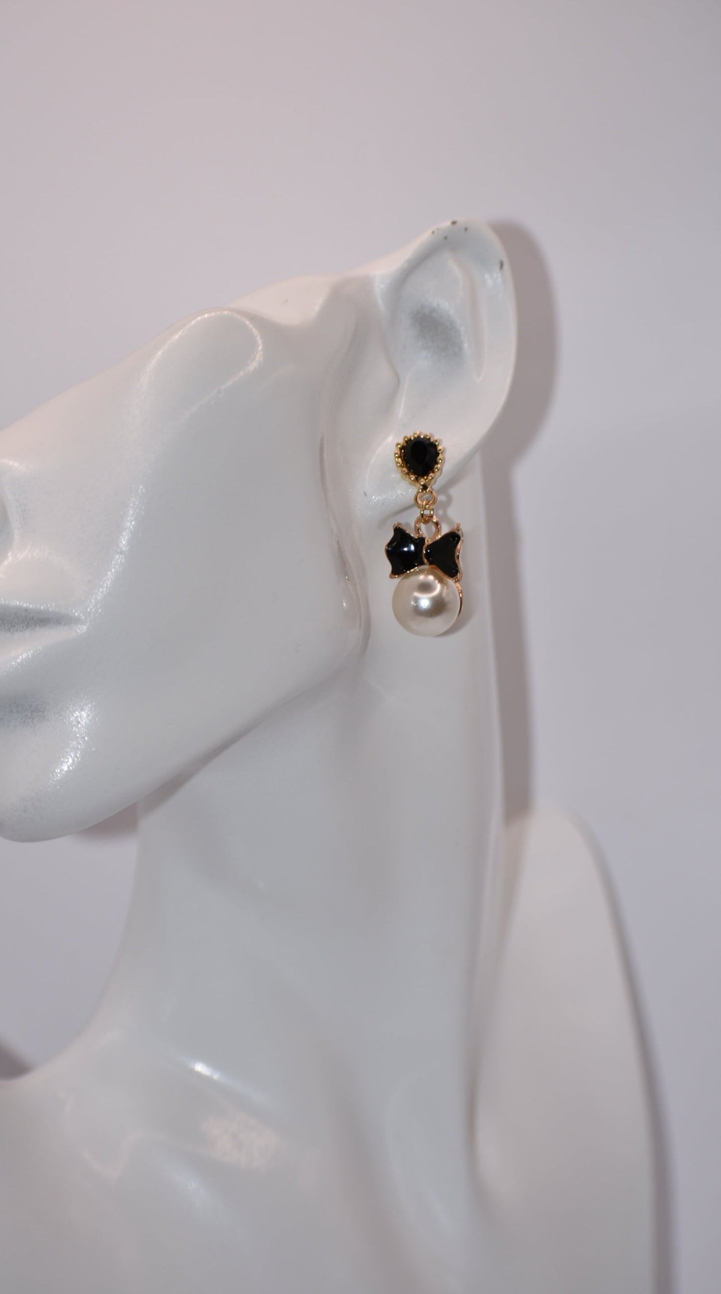 Introducing our Wedding Collection, the perfect choice for those looking for unique and stylish earrings. Our black and gold pear shaped posts feature a stunning large pearl and black tie charm, adding a touch of elegance to any outfit. Crafted with comfort and hypoallergenic materials, these earrings are perfect for sensitive ears.