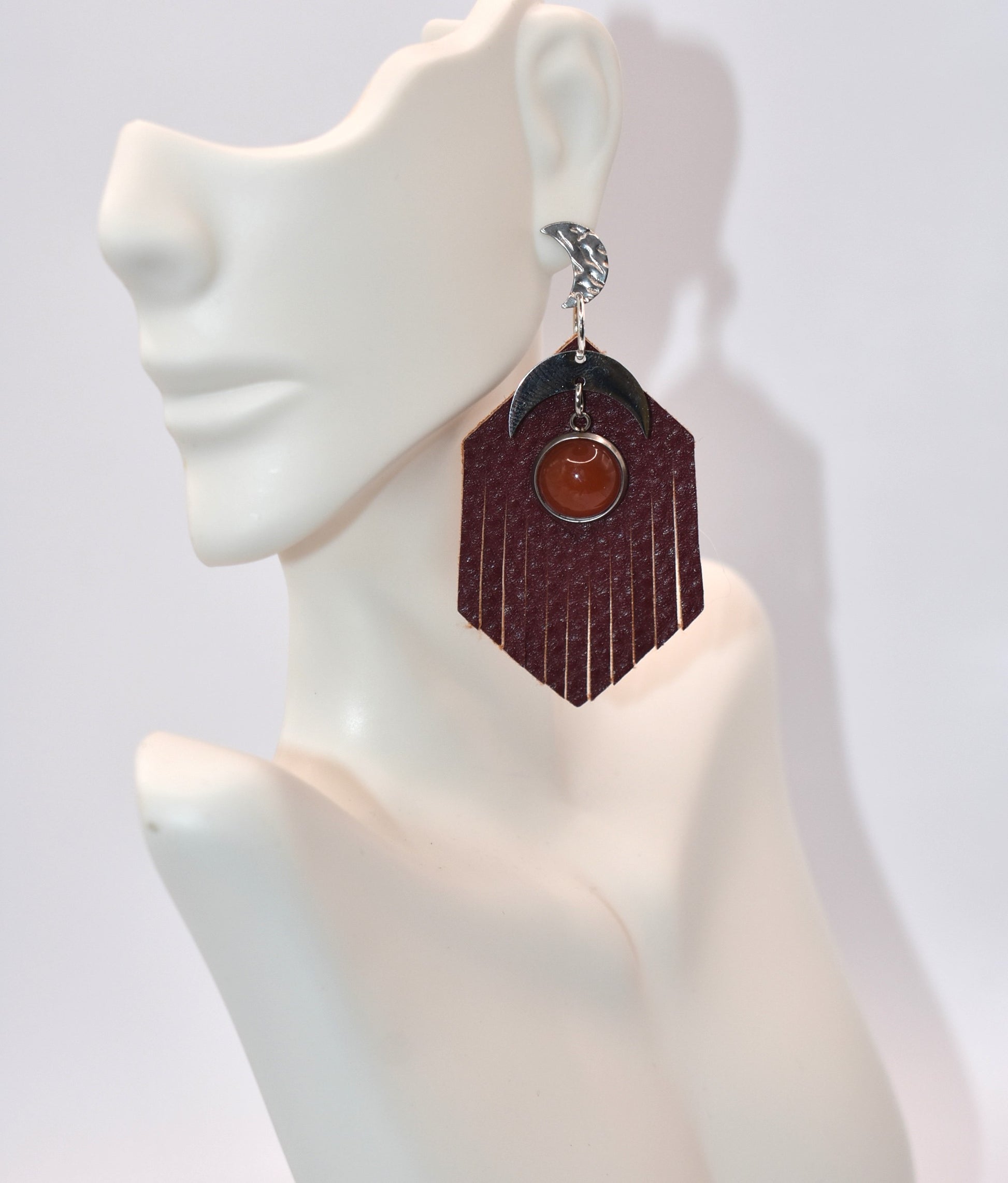 Introducing our Brown Collection! These stainless-steel hypoallergenic posts are perfect for sensitive ears. The brown fringed faux leather background adds a touch of elegance, while the stainless-steel half-moon charm and brown cabochon stone add a unique twist. Gotta have it!