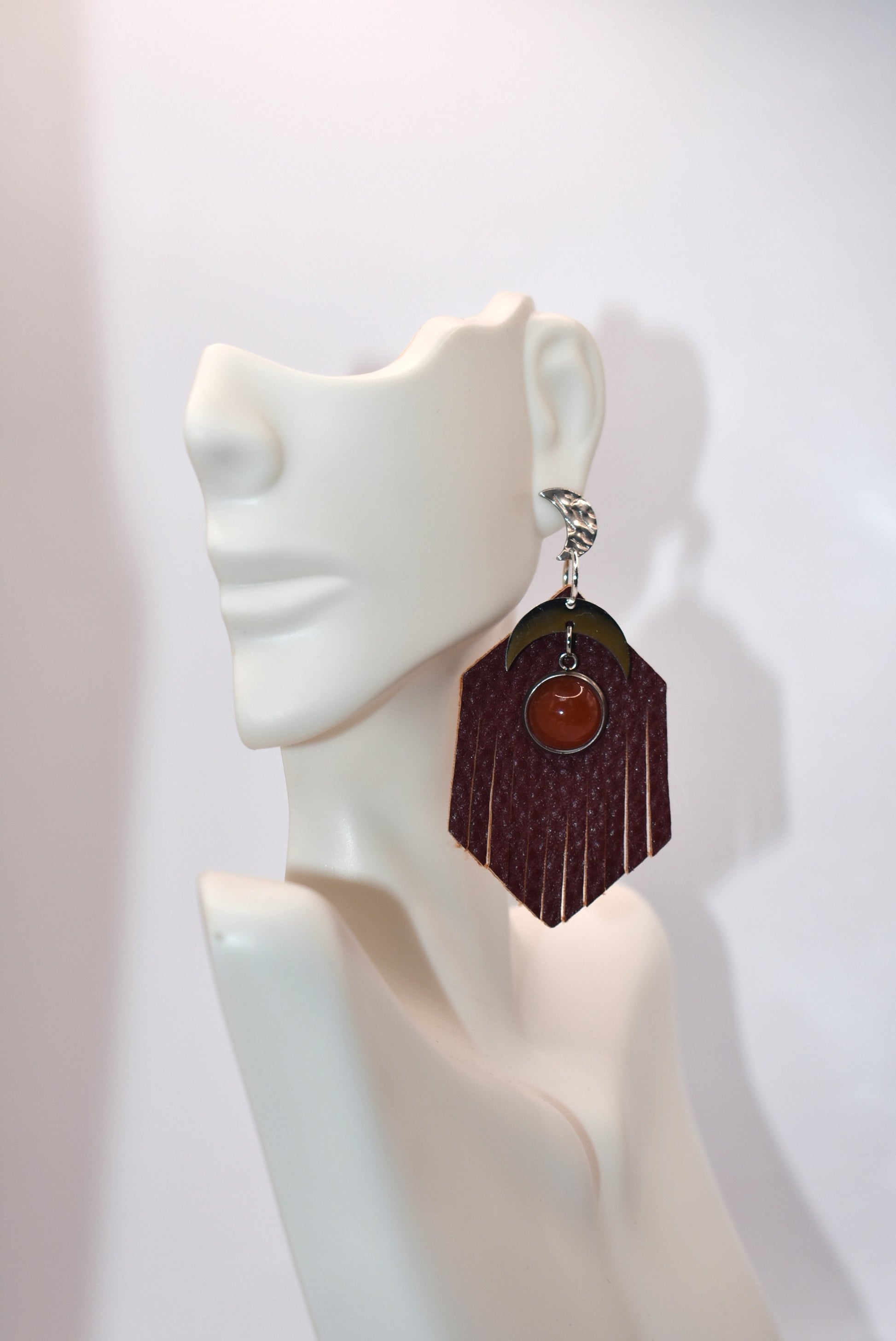 Introducing our Brown Collection! These stainless-steel hypoallergenic posts are perfect for sensitive ears. The brown fringed faux leather background adds a touch of elegance, while the stainless-steel half-moon charm and brown cabochon stone add a unique twist. Gotta have it!