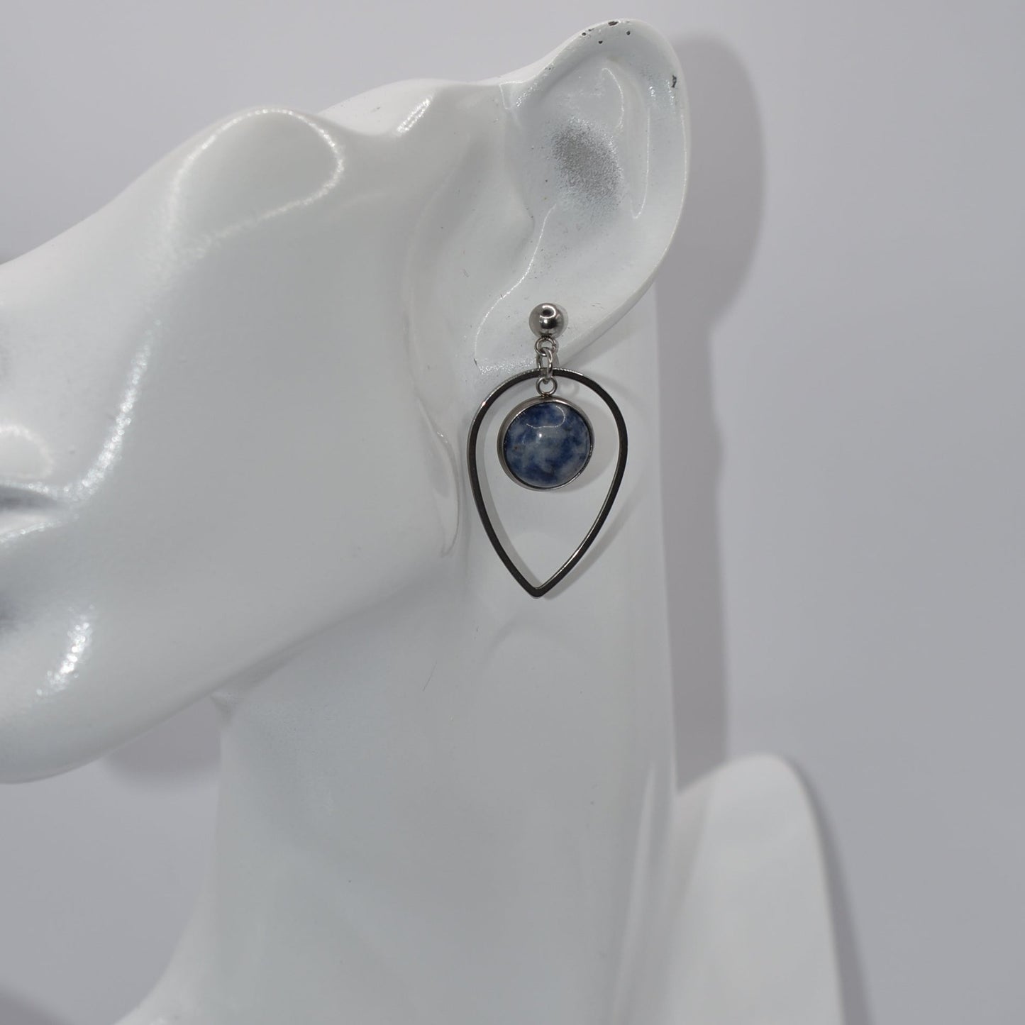 "Add some unique flair to your everyday look with our Blue Collection earrings! These silver hypoallergenic posts hold a teardrop open with a stunning cabochon stone center, ensuring both style and comfort. Perfect for all-day wear. (Your ears will thank you.)"