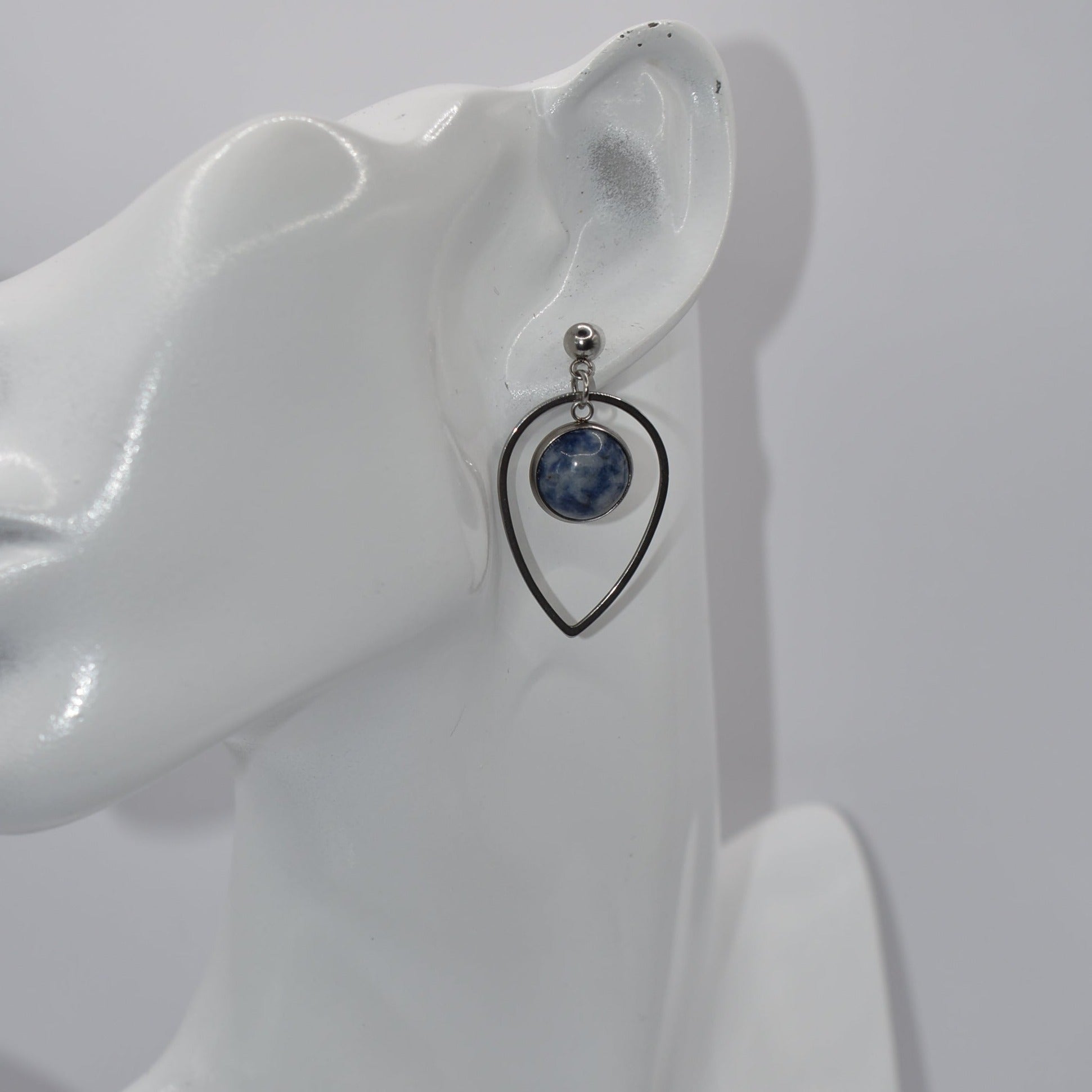 "Add some unique flair to your everyday look with our Blue Collection earrings! These silver hypoallergenic posts hold a teardrop open with a stunning cabochon stone center, ensuring both style and comfort. Perfect for all-day wear. (Your ears will thank you.)"