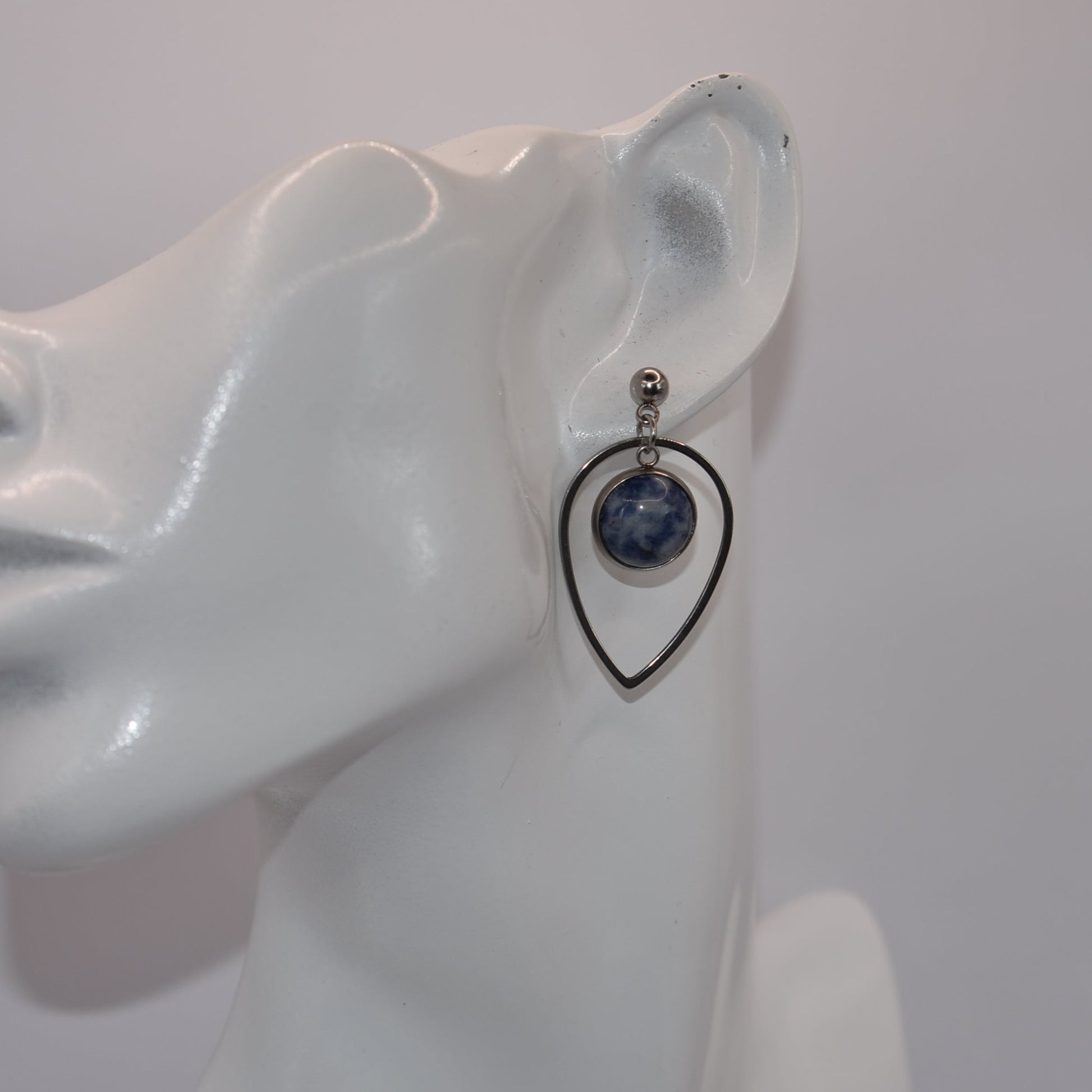 "Add some unique flair to your everyday look with our Blue Collection earrings! These silver hypoallergenic posts hold a teardrop open with a stunning cabochon stone center, ensuring both style and comfort. Perfect for all-day wear. (Your ears will thank you.)"