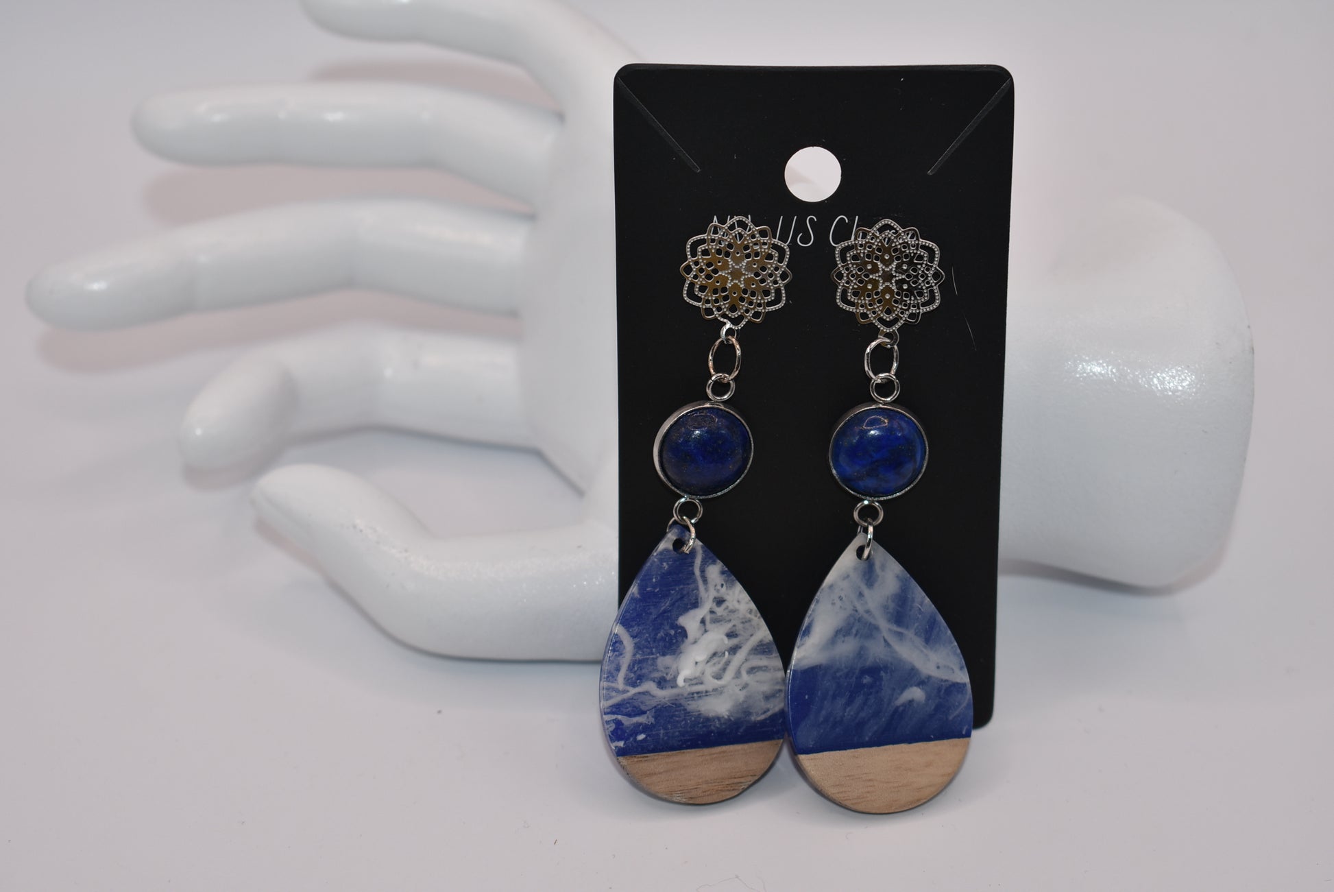 Unleash your unique style with the Blue Collection! This one-of-a-kind piece features a blue cabochon stone on a long silver filigree post, with a resin and wood teardrop that hangs around 2 1/2 inches for a chic look. Hypoallergenic posts make it super comfortable for sensitive ears.