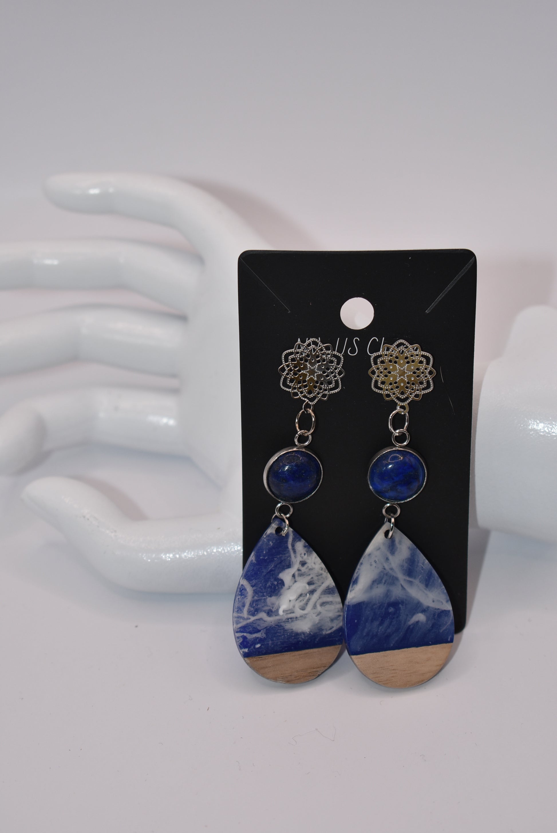 Unleash your unique style with the Blue Collection! This one-of-a-kind piece features a blue cabochon stone on a long silver filigree post, with a resin and wood teardrop that hangs around 2 1/2 inches for a chic look. Hypoallergenic posts make it super comfortable for sensitive ears.