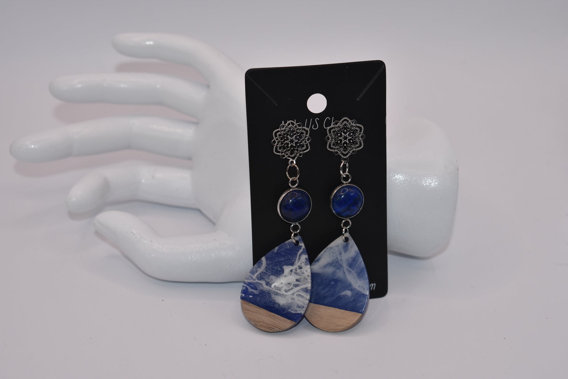 Unleash your unique style with the Blue Collection! This one-of-a-kind piece features a blue cabochon stone on a long silver filigree post, with a resin and wood teardrop that hangs around 2 1/2 inches for a chic look. Hypoallergenic posts make it super comfortable for sensitive ears.