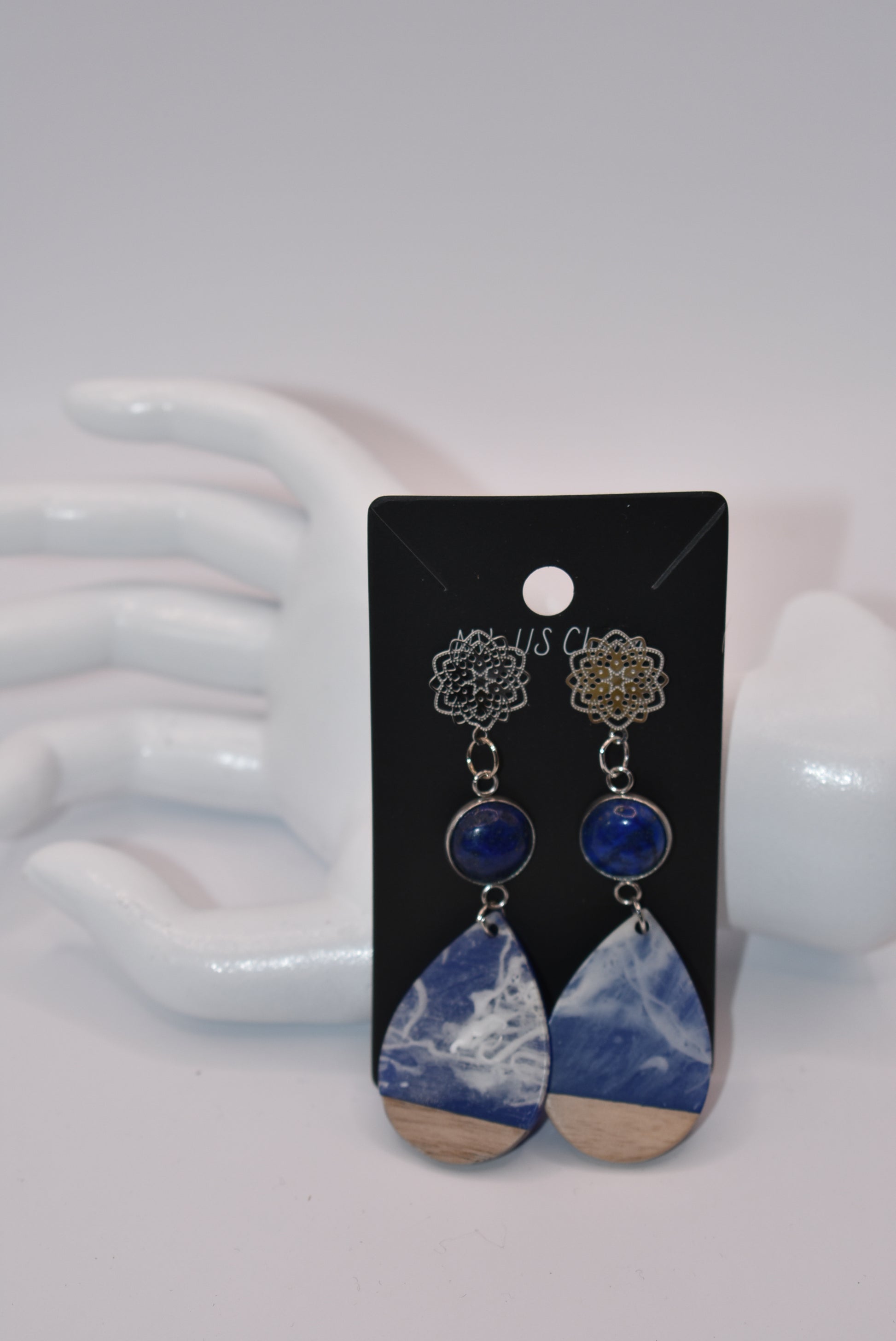 Unleash your unique style with the Blue Collection! This one-of-a-kind piece features a blue cabochon stone on a long silver filigree post, with a resin and wood teardrop that hangs around 2 1/2 inches for a chic look. Hypoallergenic posts make it super comfortable for sensitive ears.