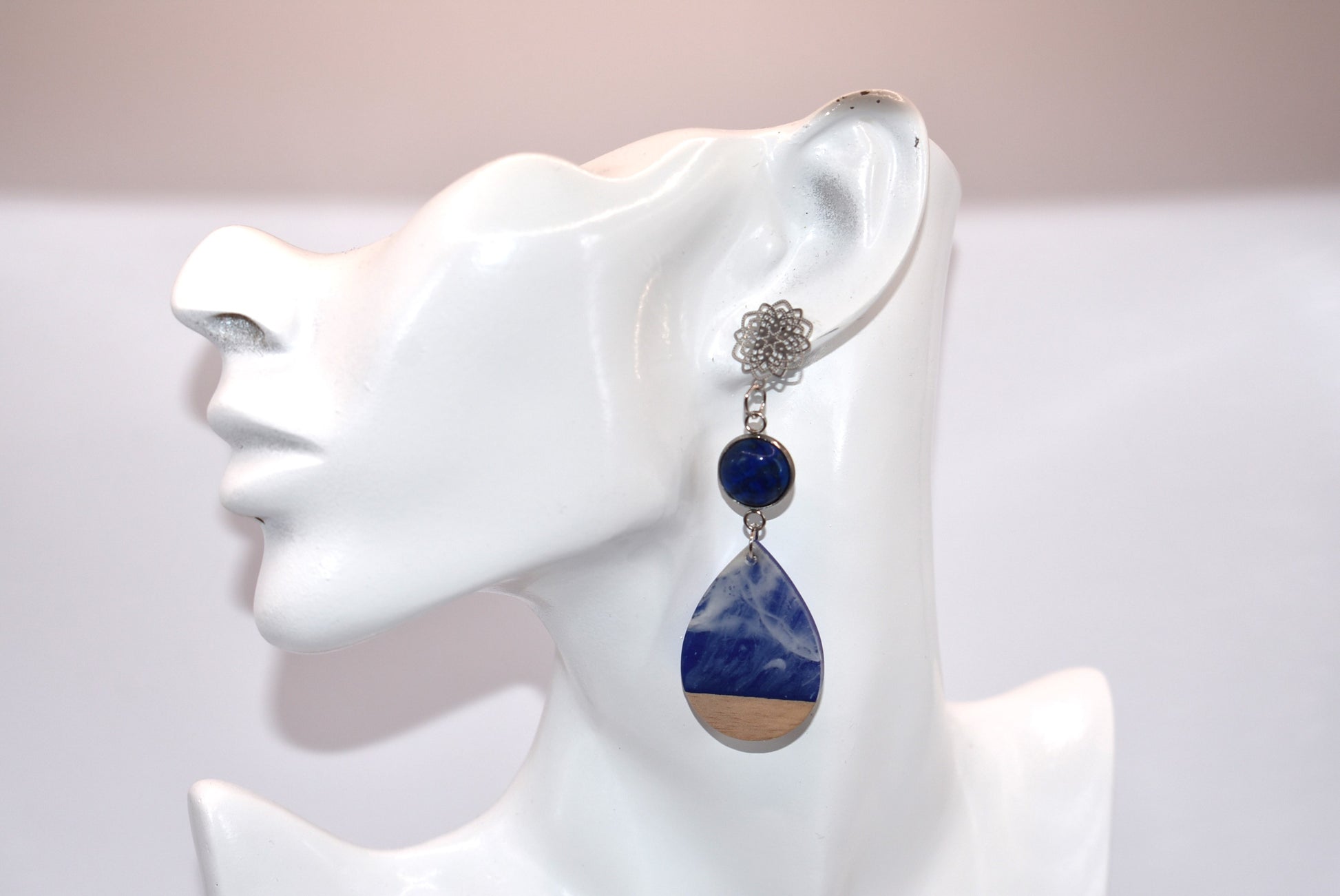 Unleash your unique style with the Blue Collection! This one-of-a-kind piece features a blue cabochon stone on a long silver filigree post, with a resin and wood teardrop that hangs around 2 1/2 inches for a chic look. Hypoallergenic posts make it super comfortable for sensitive ears.