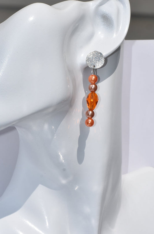 The Orange Collection 7 earrings offer an elegant combination of orange, bronze pearls and orange crystals, all set in shiny silver posts. Perfectly lightweight for all-day wear, each pair hangs perfectly in length for a subtly glamorous look.