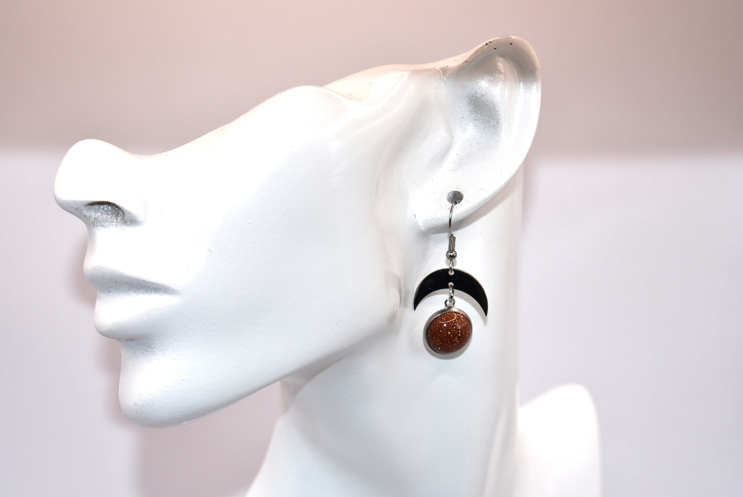 Introducing the Brown Collection - stylish stainless-steel earrings with a cabochon copper sparkly stone. These earrings feature a comfortable half-moon design and pair perfectly with any outfit (you'll love them!). Upgrade your accessory game and add a touch of sparkle with these unique earrings.