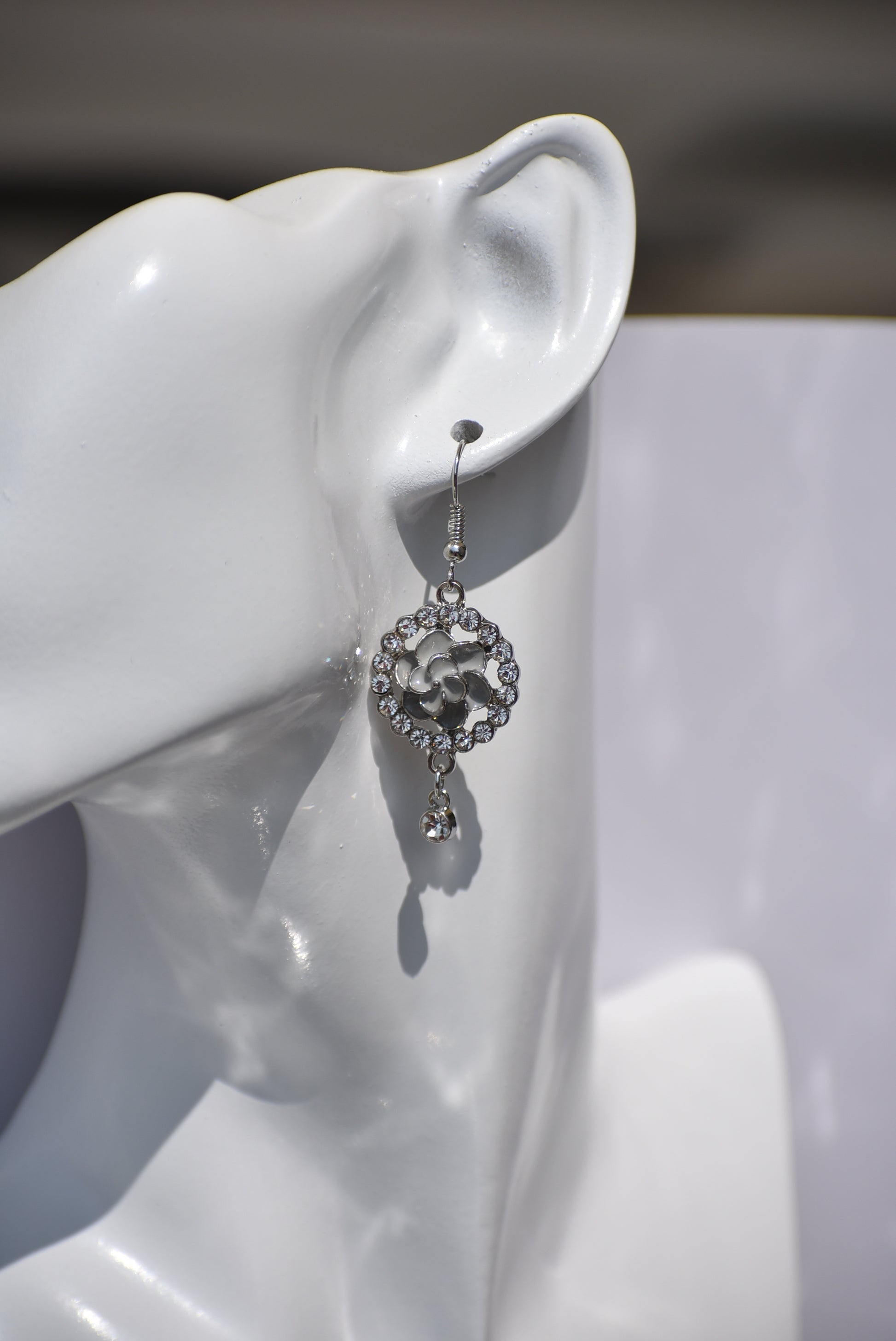 These Gray Collection 9 earrings provide a unique and sophisticated look. Featuring a pretty gray flower surrounded by crystals and a small crystal hanging, these silver hook earrings will add sparkle and elegance to any outfit. With intricate details and luxurious design, these earrings are a must-have addition to any jewelry collection.