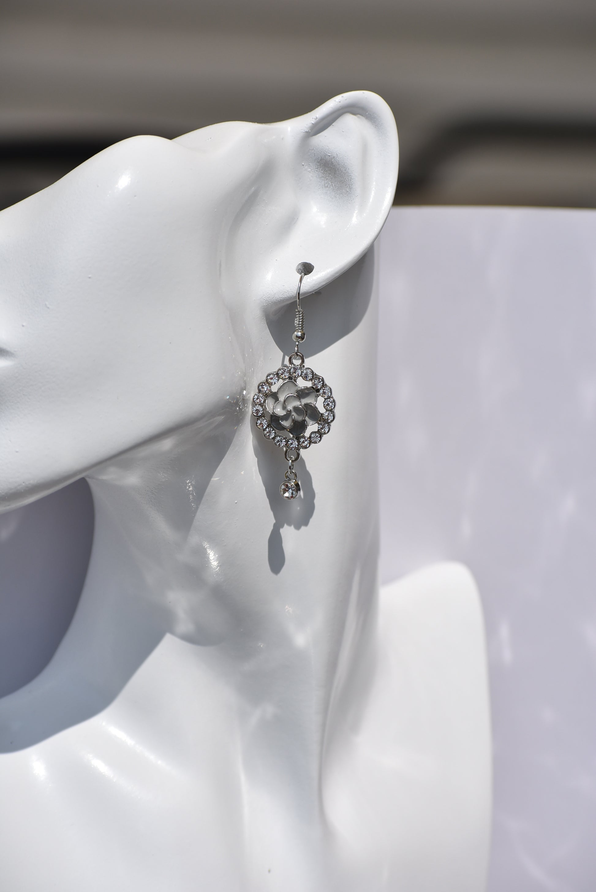 These Gray Collection 9 earrings provide a unique and sophisticated look. Featuring a pretty gray flower surrounded by crystals and a small crystal hanging, these silver hook earrings will add sparkle and elegance to any outfit. With intricate details and luxurious design, these earrings are a must-have addition to any jewelry collection.