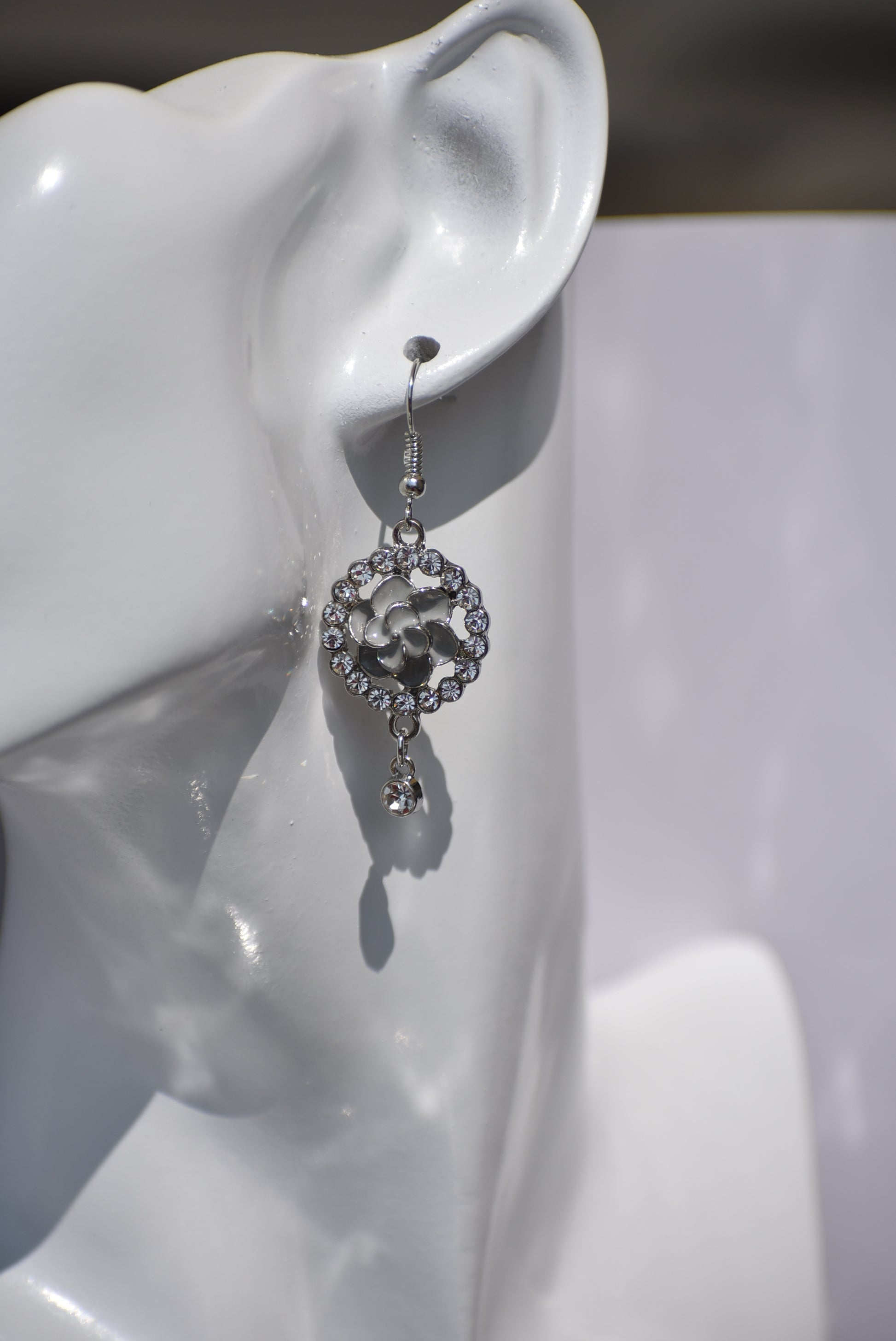 These Gray Collection 9 earrings provide a unique and sophisticated look. Featuring a pretty gray flower surrounded by crystals and a small crystal hanging, these silver hook earrings will add sparkle and elegance to any outfit. With intricate details and luxurious design, these earrings are a must-have addition to any jewelry collection.