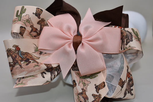 Add a splash of charm with this one-of-a-kind cowgirl bow! 🤠 A large brown grosgrain ribbon showcases a delicate cowgirl motif, topped with a sweet peach bow 🎀. Securely fastened with an alligator clip, it stays put while you shine! Perfect for little cowgirls ready to twirl and play. 🌟🐴