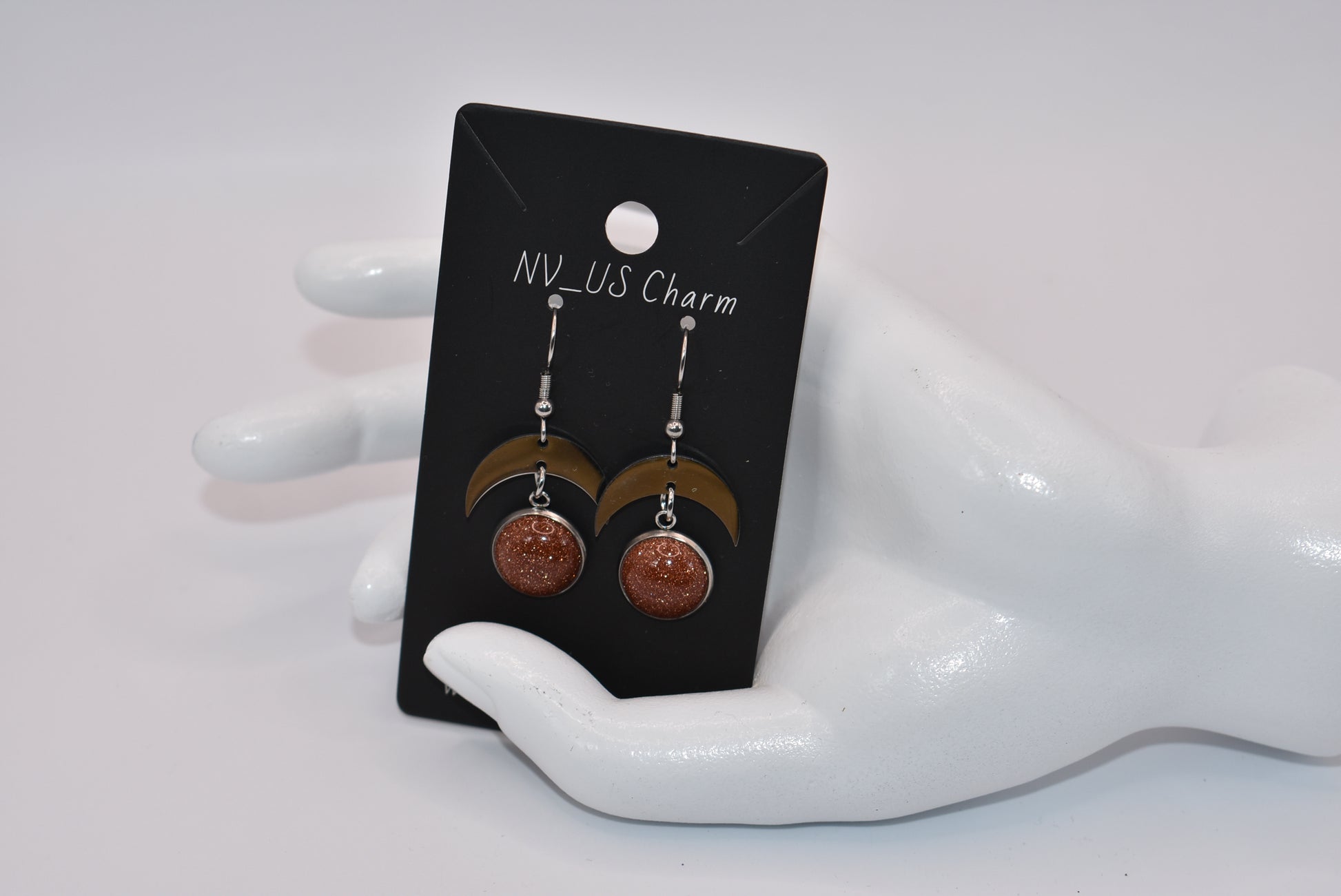 Introducing the Brown Collection - stylish stainless-steel earrings with a cabochon copper sparkly stone. These earrings feature a comfortable half-moon design and pair perfectly with any outfit (you'll love them!). Upgrade your accessory game and add a touch of sparkle with these unique earrings.