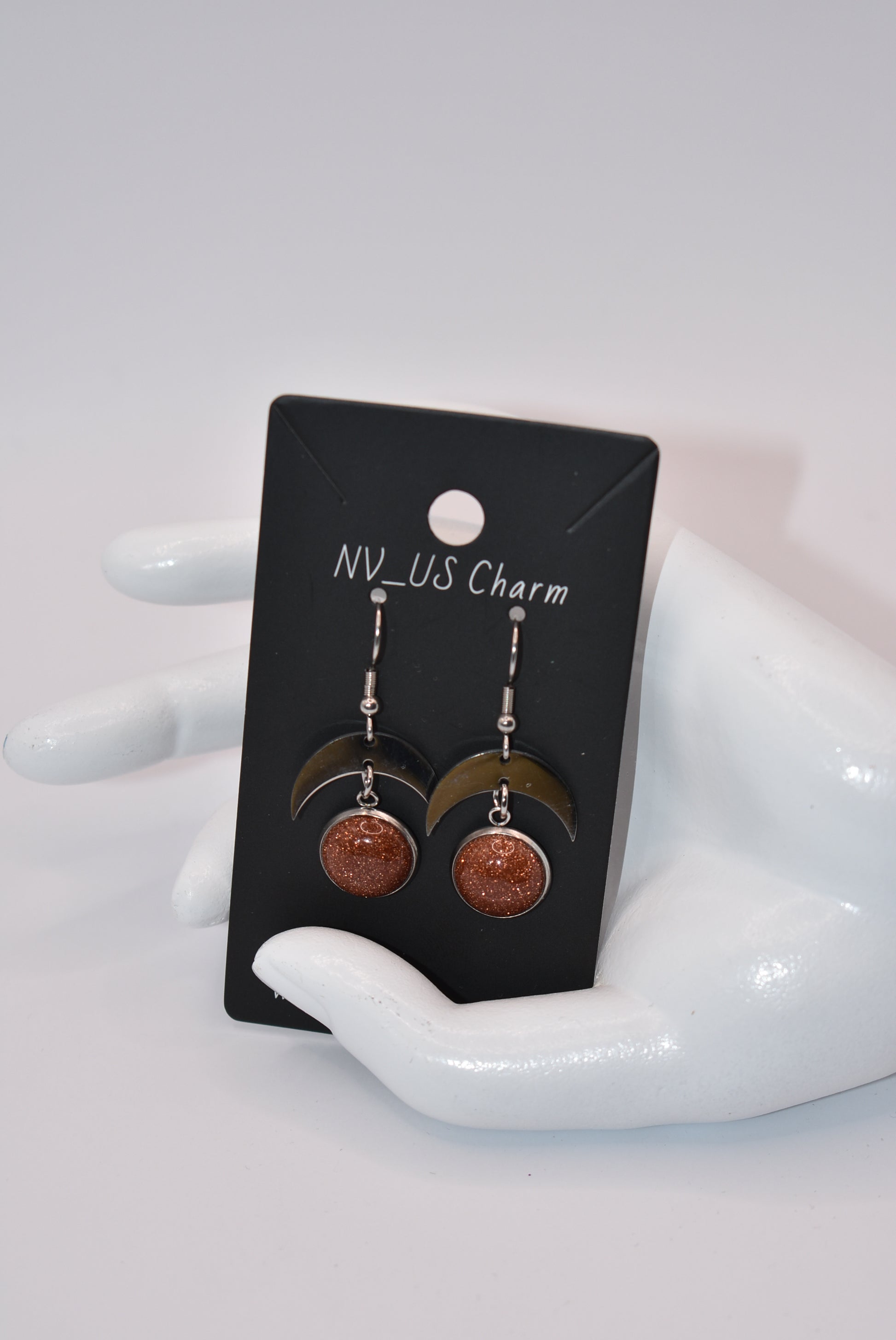 Introducing the Brown Collection - stylish stainless-steel earrings with a cabochon copper sparkly stone. These earrings feature a comfortable half-moon design and pair perfectly with any outfit (you'll love them!). Upgrade your accessory game and add a touch of sparkle with these unique earrings.